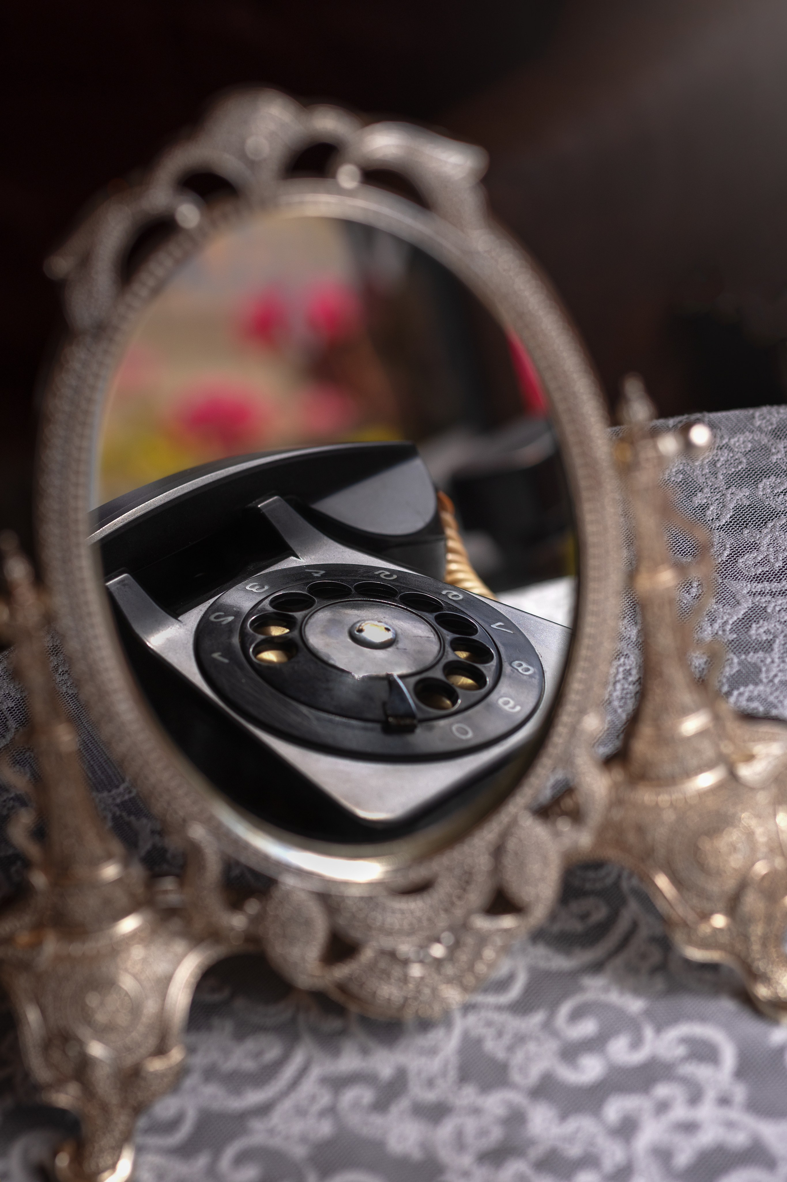 в настольном зеркале отражается черный старинный телефон