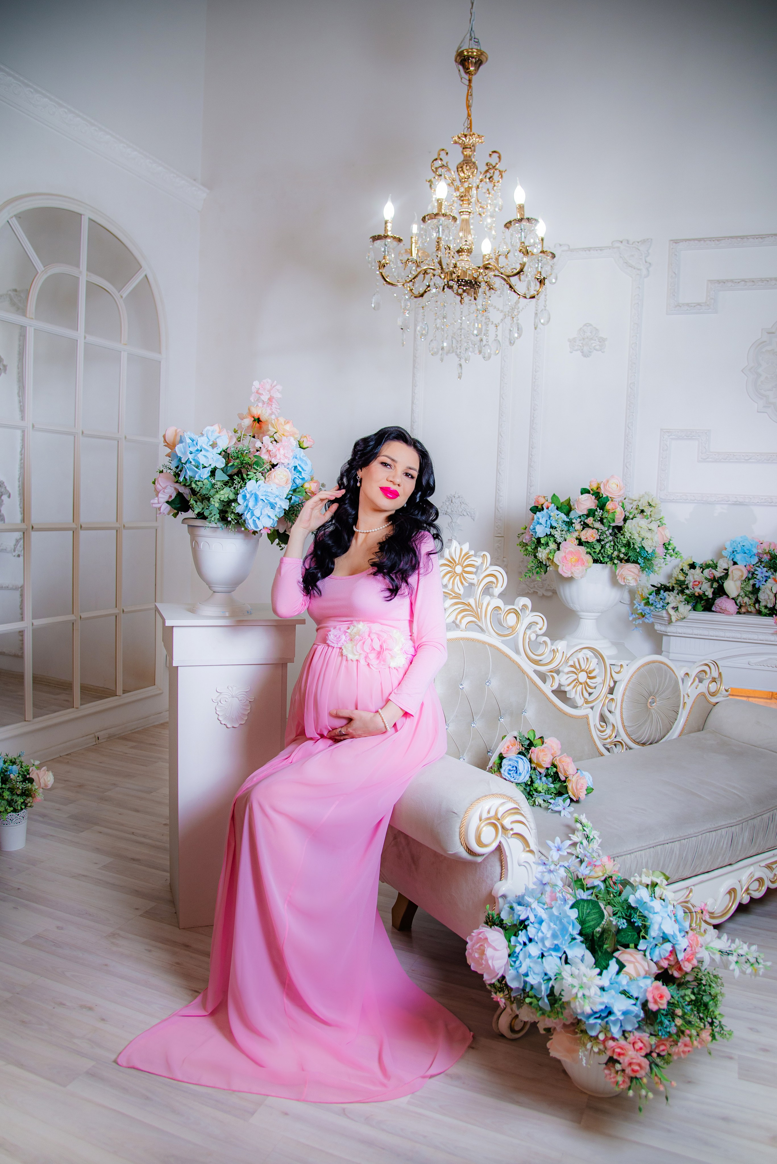 Фотосессия беременных в фотостудии в Уфе: будущая мама в элегантном платье из проката, с профессиональным макияжем и прической. Она счастливо позирует на фоне стильного интерьера, отражая красоту и нежность материнства.