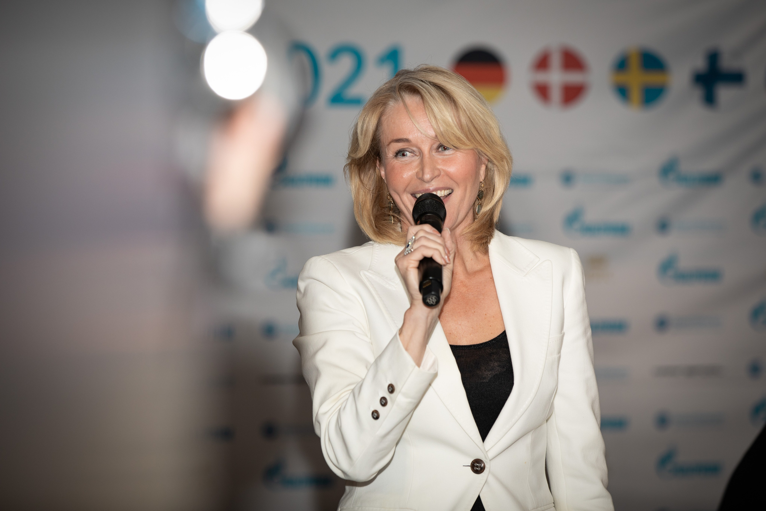 Ведущая крупным планом на фоне пресс-вола на международной регате.