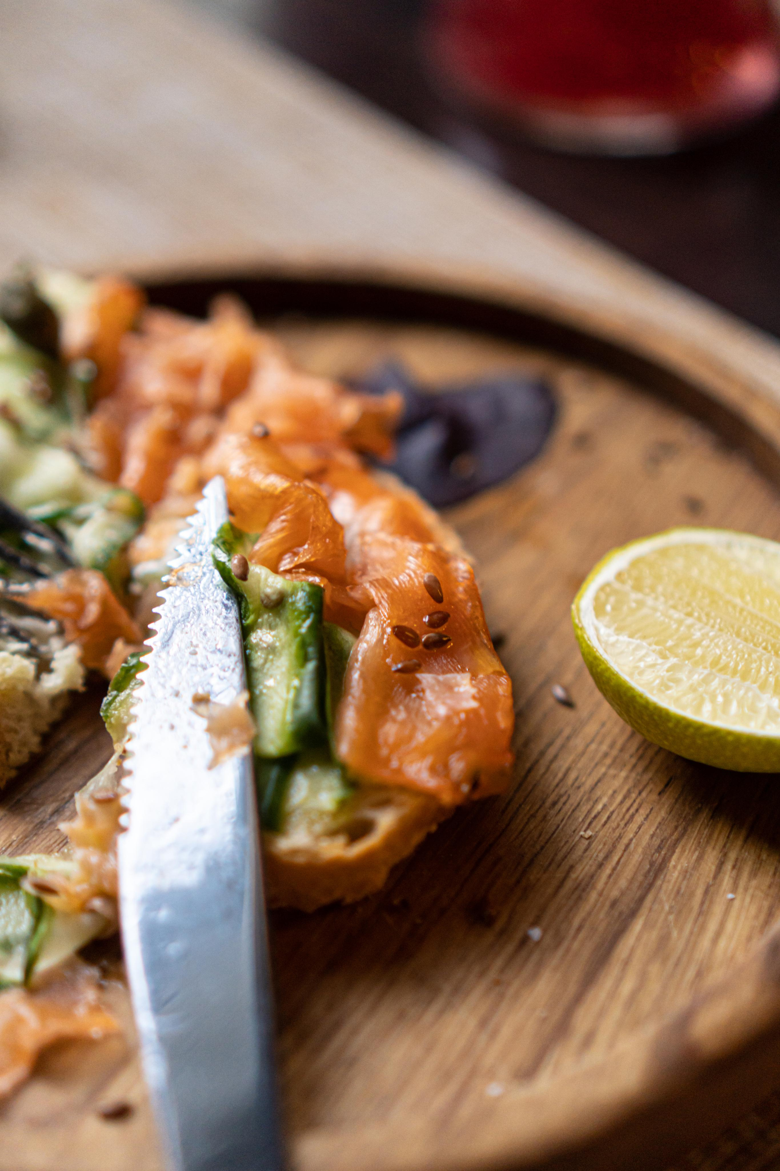 бутерброд с семгой и лаймом на деревянной тарелке с ножом