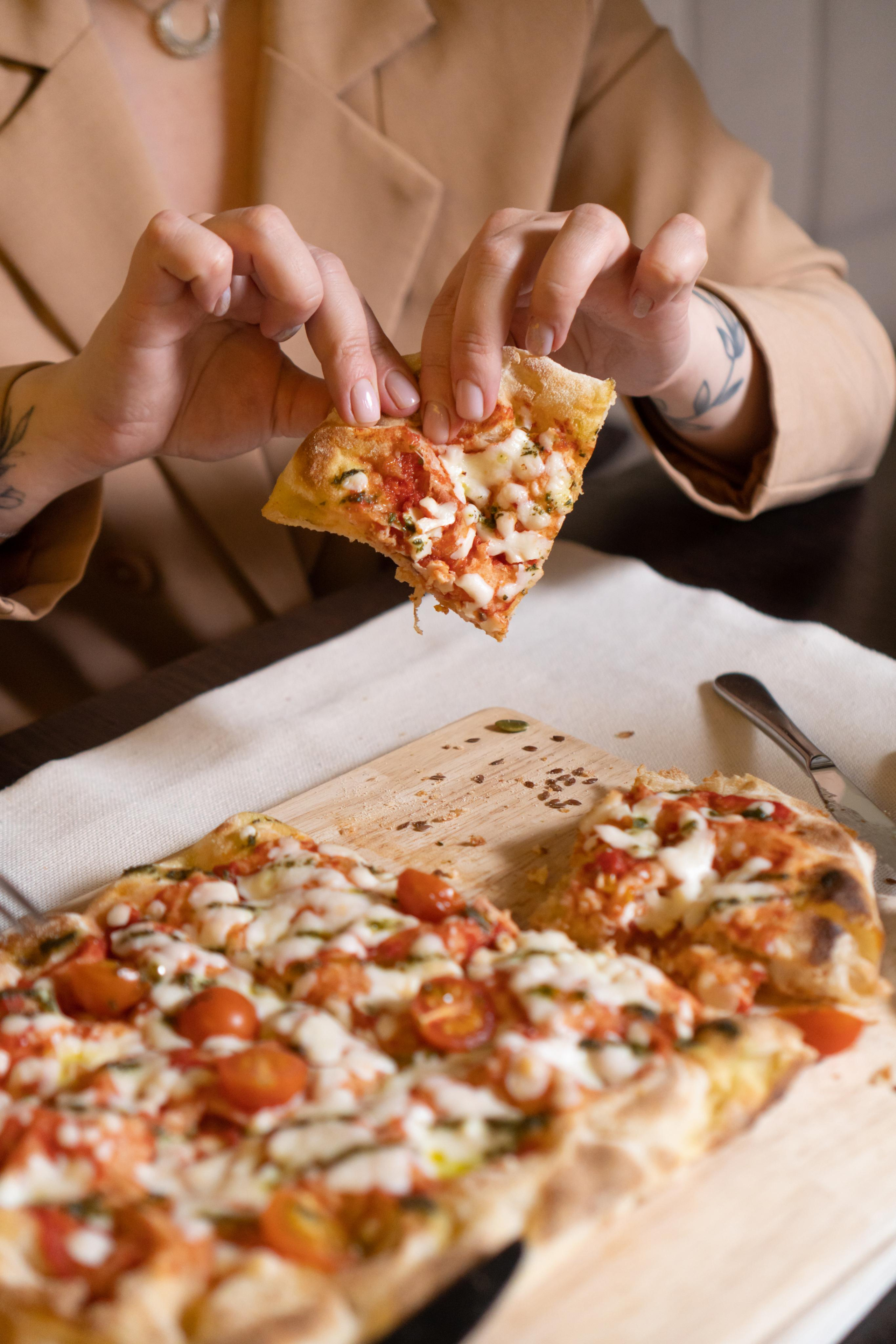 девушка берет кусочек пиццы в ресторане