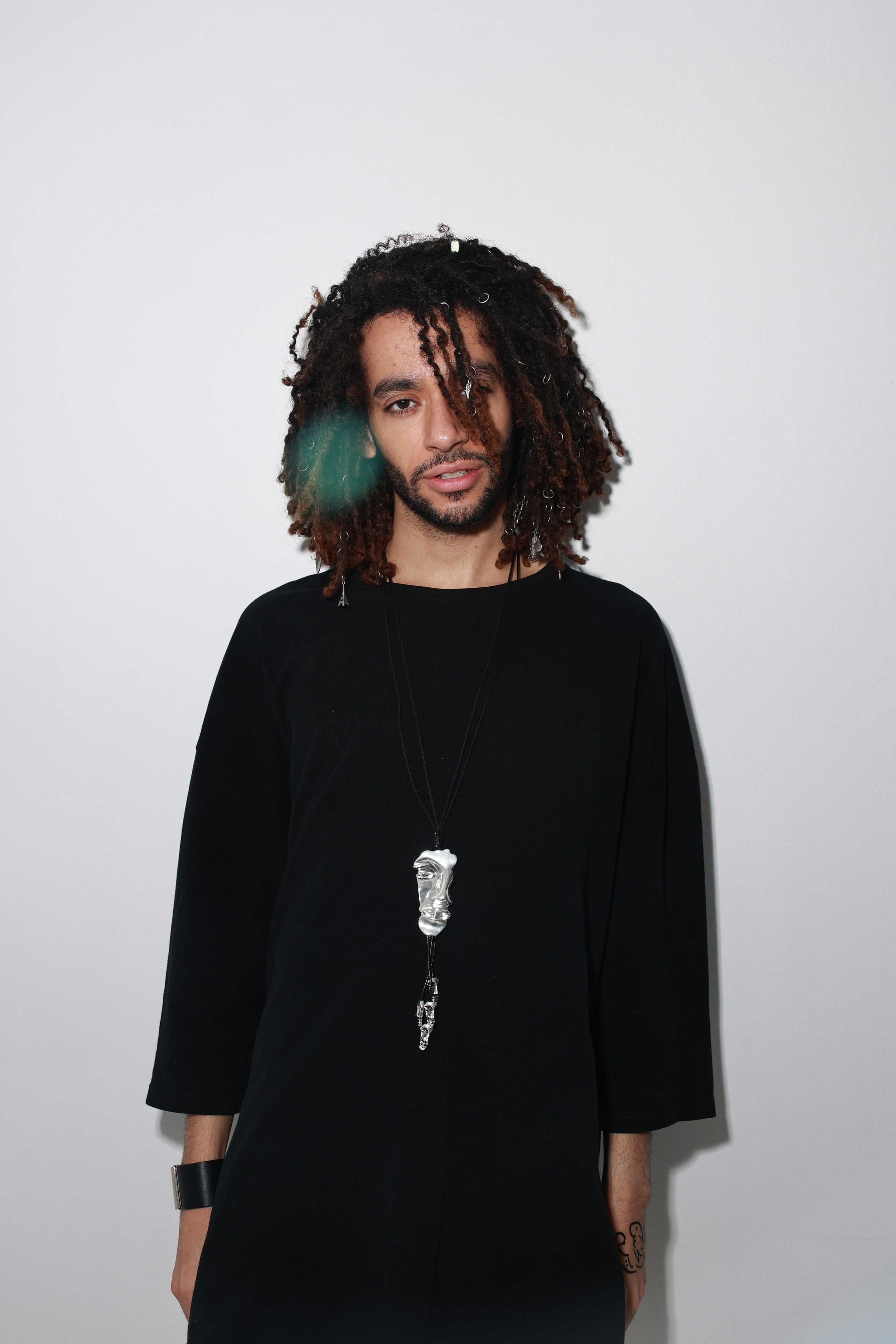 Темнокожий парень с длинными кудрявыми волосами в черной одежде