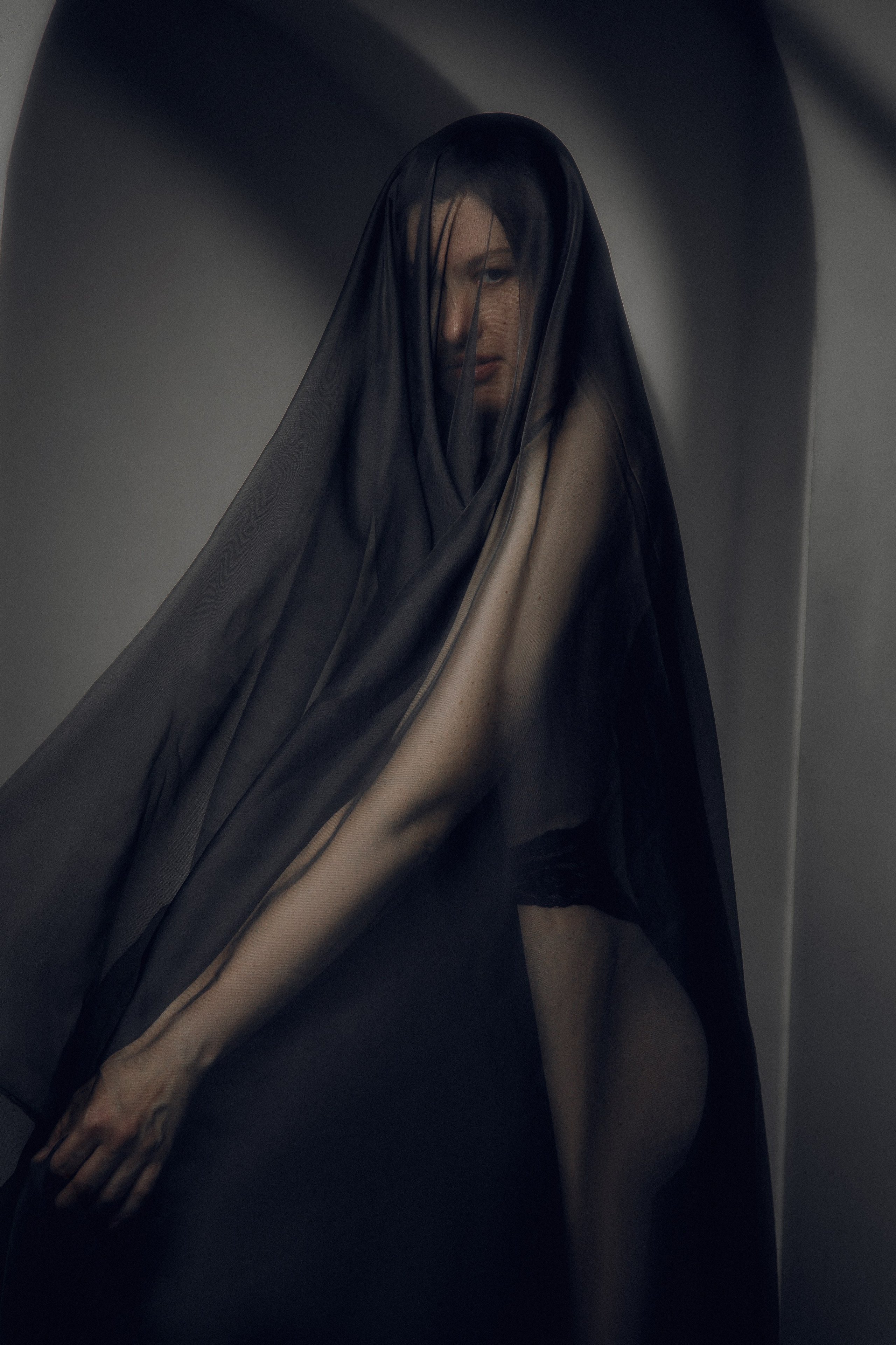 Студийный портрет девушки с использованием черной ткани.