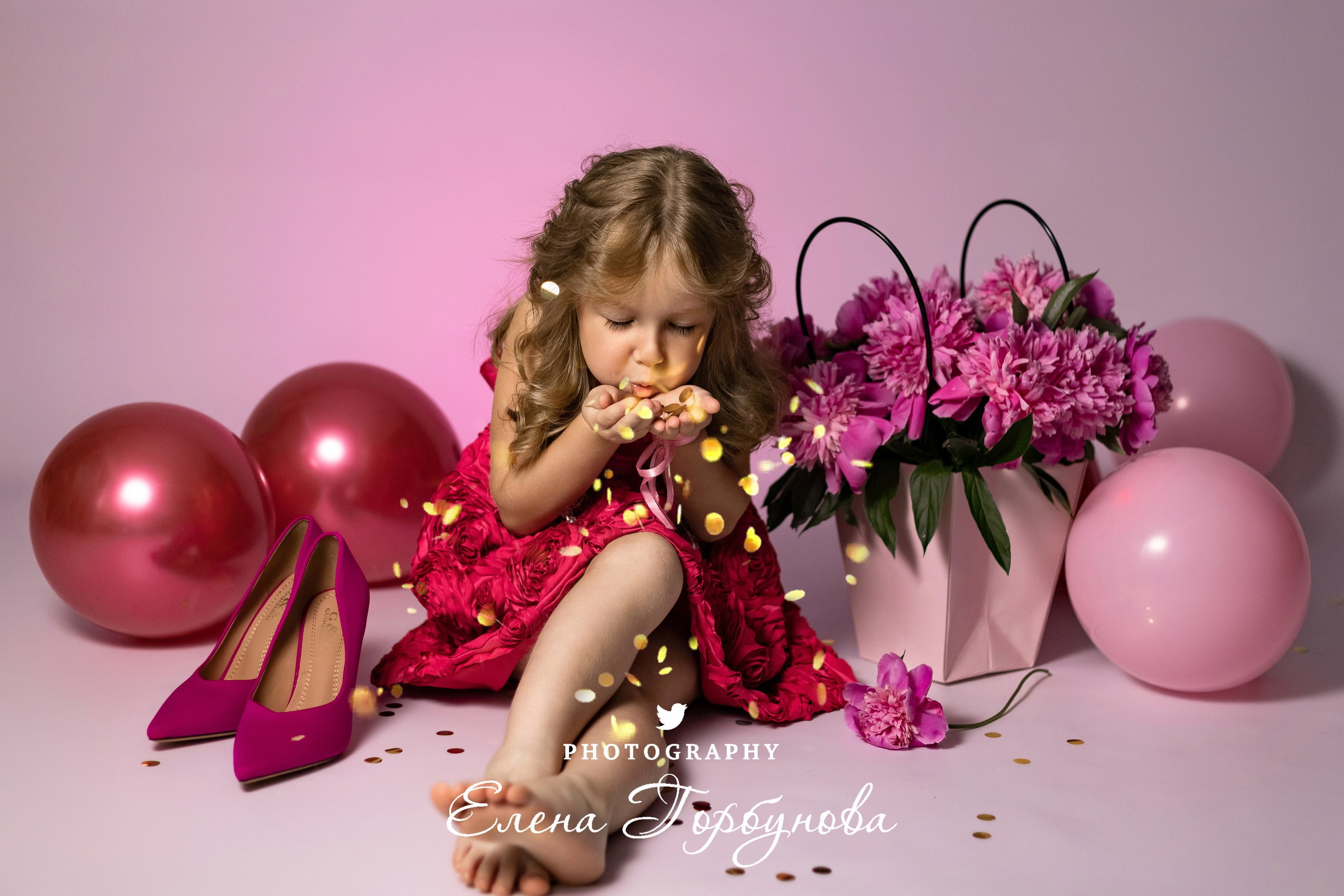 девочка модница в розовом с пионами раздувает блестки на фотосессии в студии