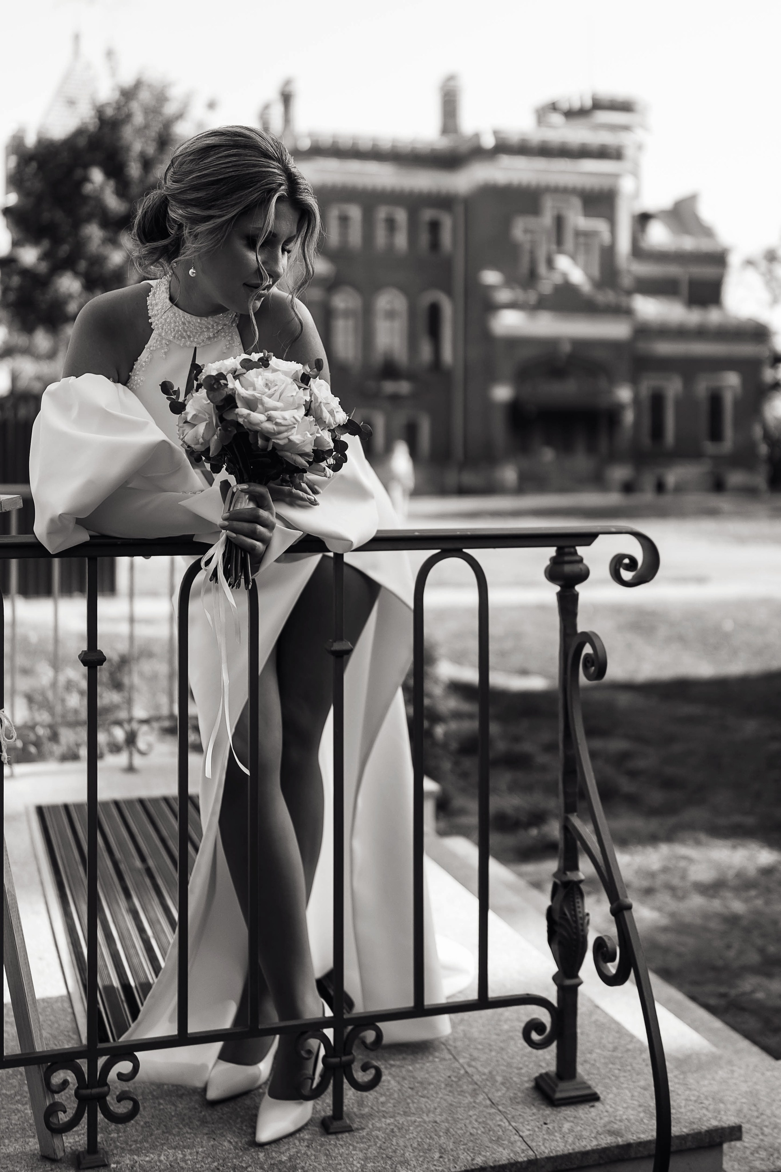 Невеста опирается на перила во время свадебной фотосессии в замке Ольденбургских в Воронеже