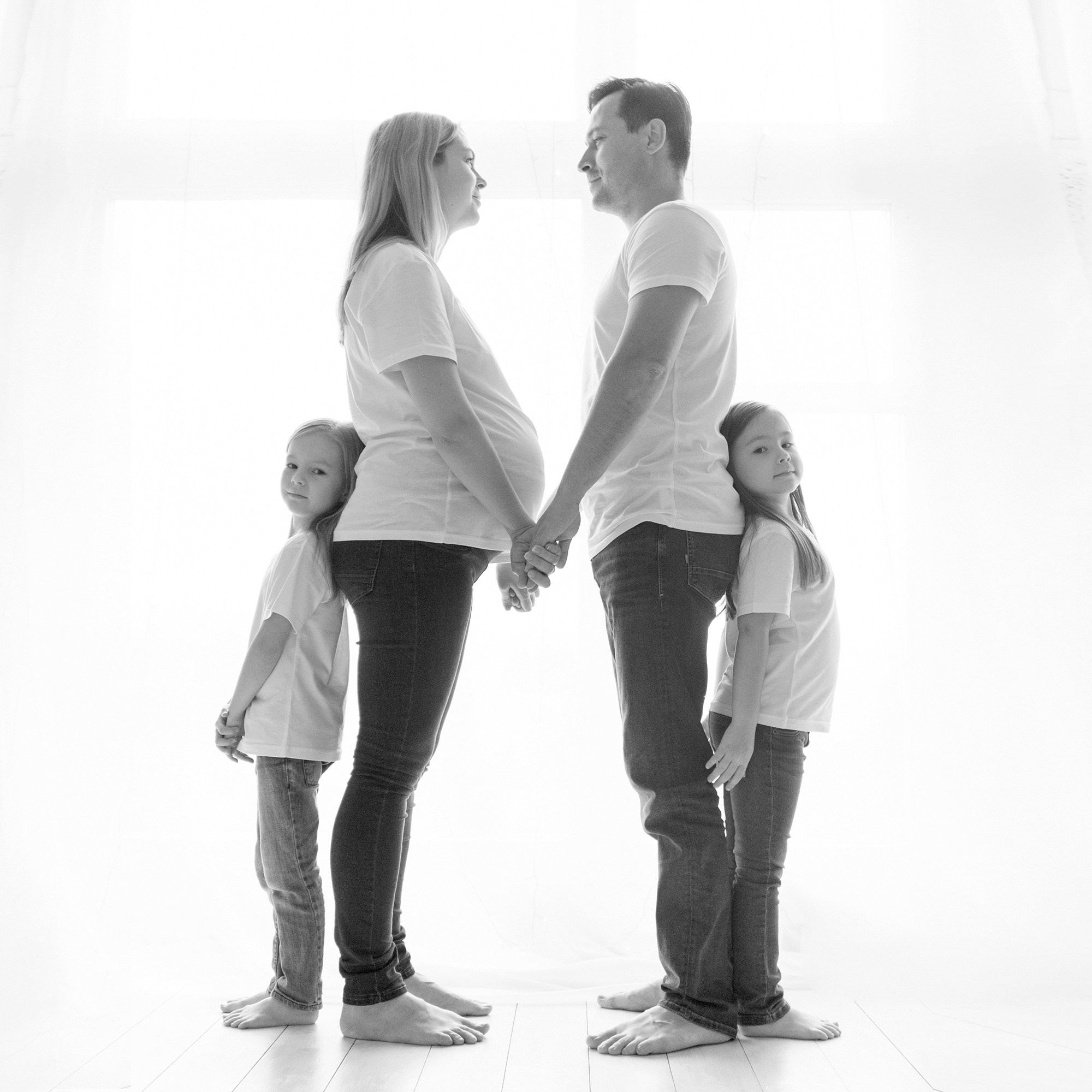 Родители, обнимающие своих детей на фоне окна 