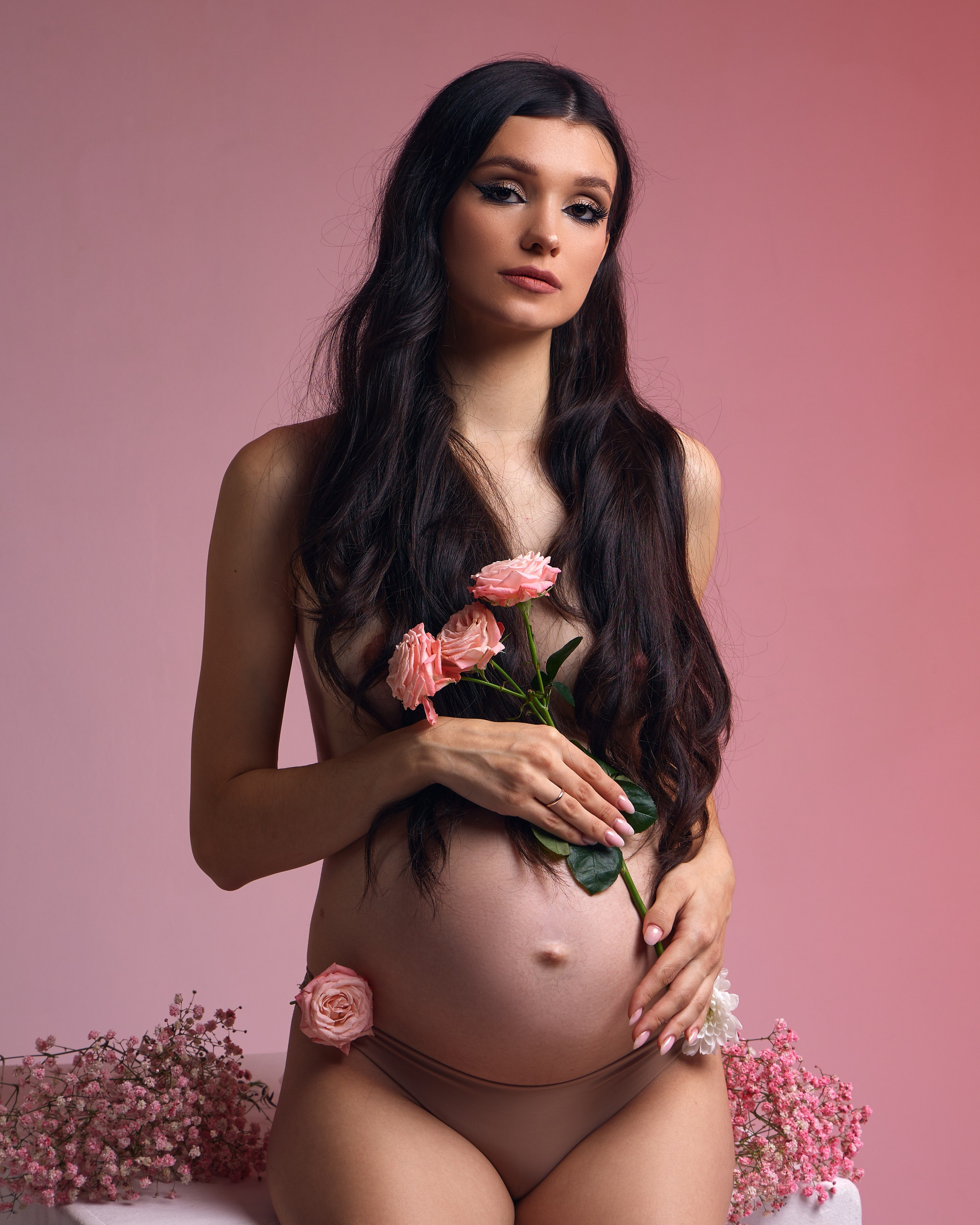 Беременная девушка в фотостудии в цветах