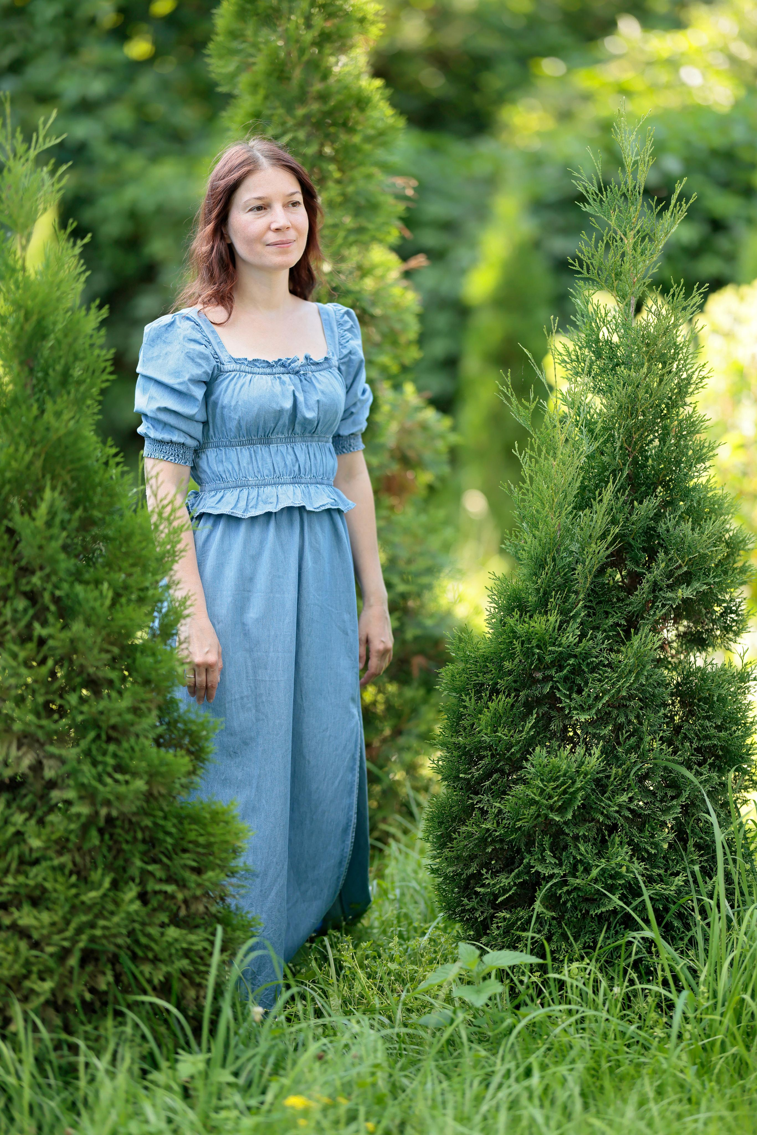 Ростовой портрет женщины в голубом платье на фоне зелени.