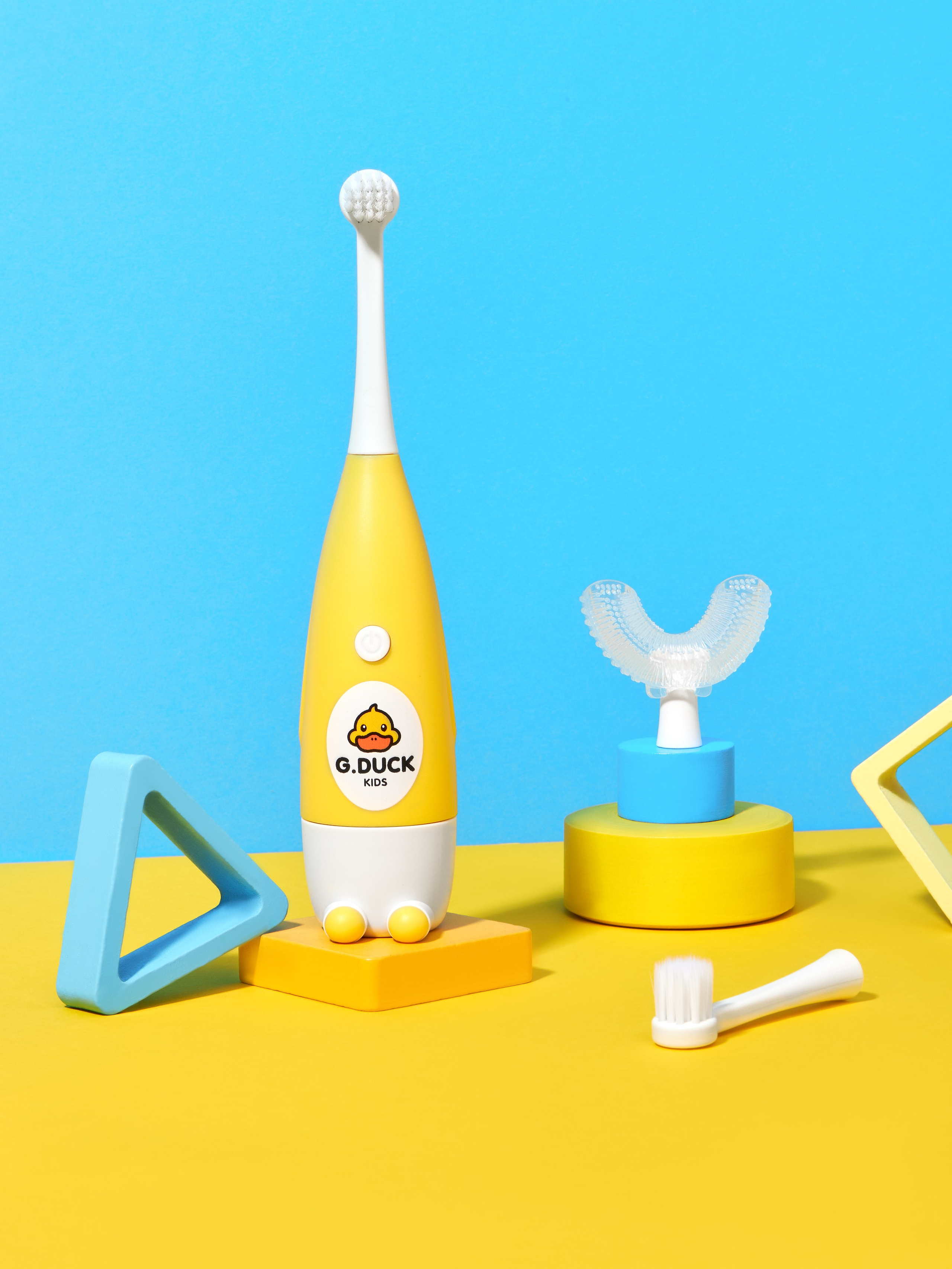 Предметная рекламная фотосъёмка детской электрической зубной щетки желтого цвета на голубом и желтом фоне