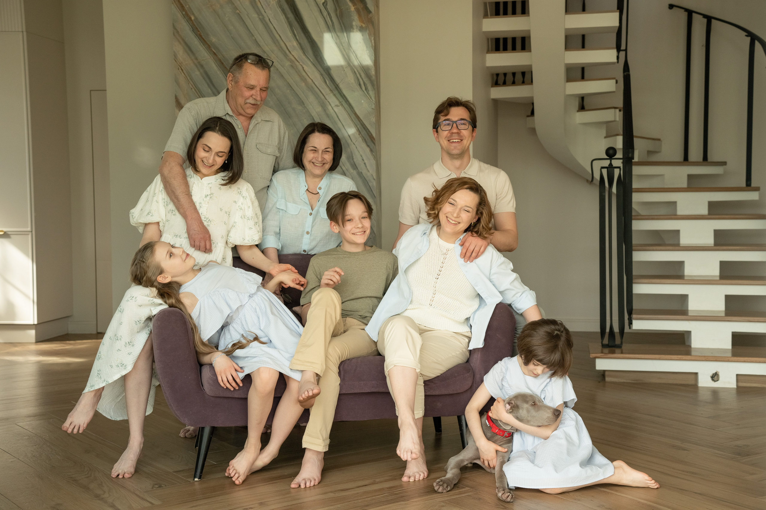 Фото большой семьи состоящей из трех поколений. Они сидят на диване в гостинной комнате собственного дома.