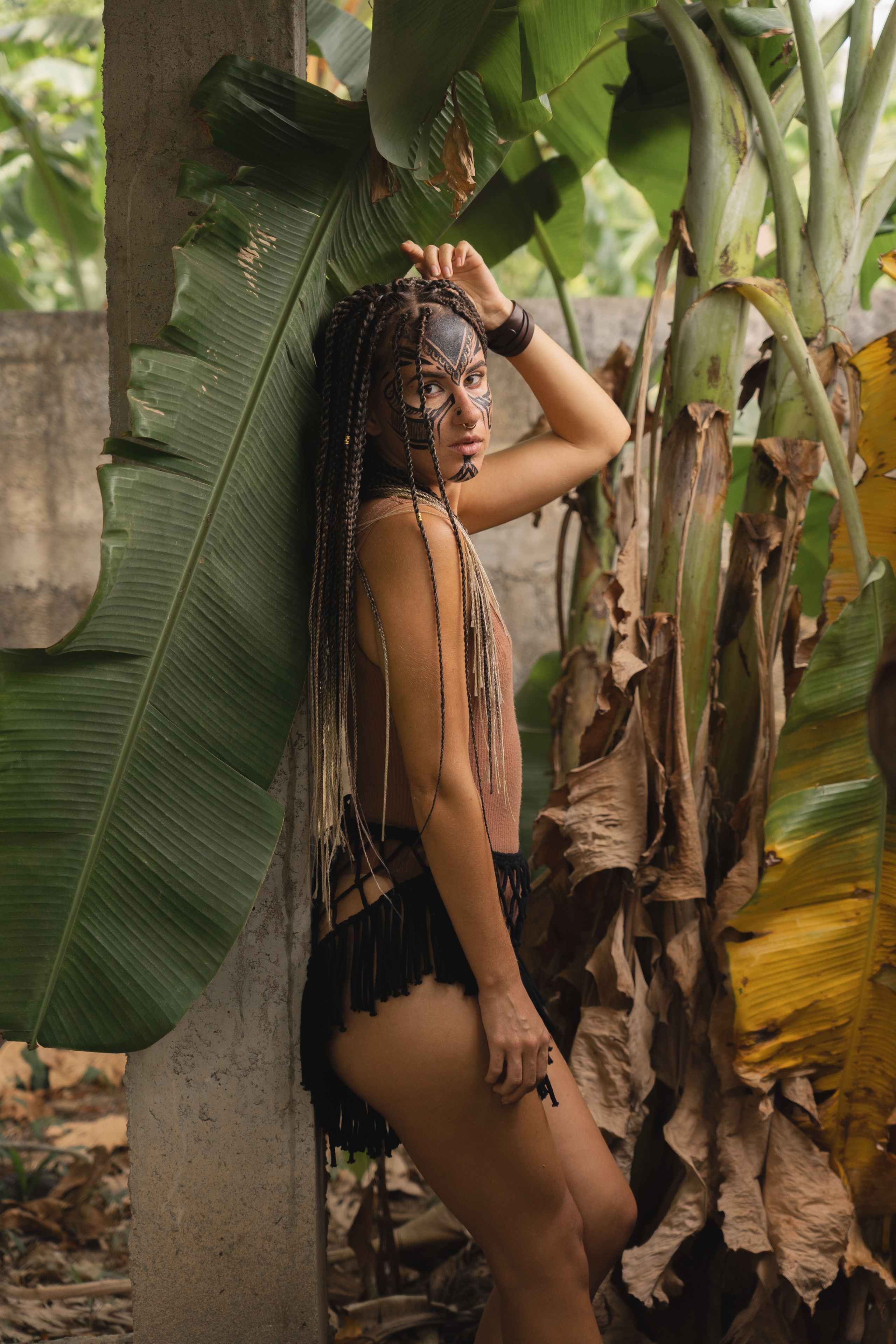 a girl with braids and tribal face paint surrounded by greenery