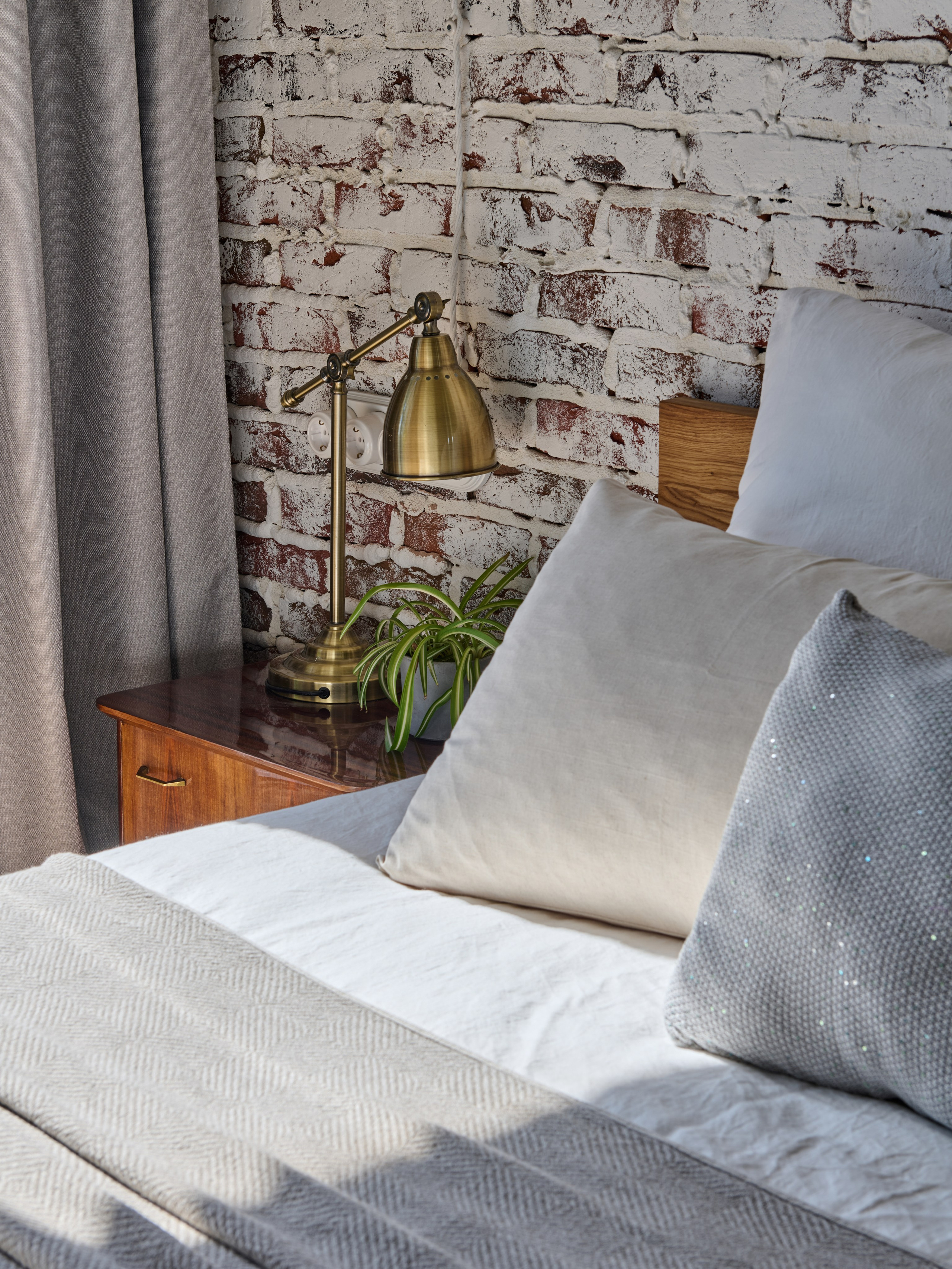 Деталь спальни: подушки и плед, прикроватный светильник