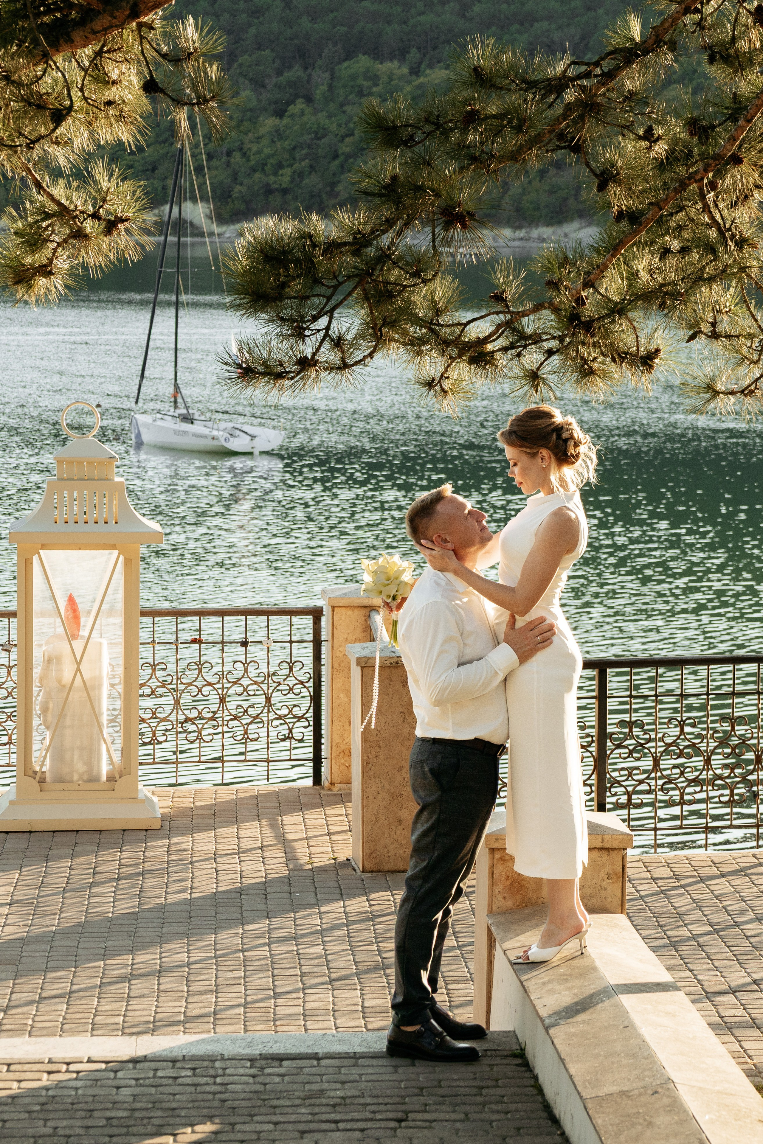 Невеста и жених держатся за руки у бирюзовой воды озера