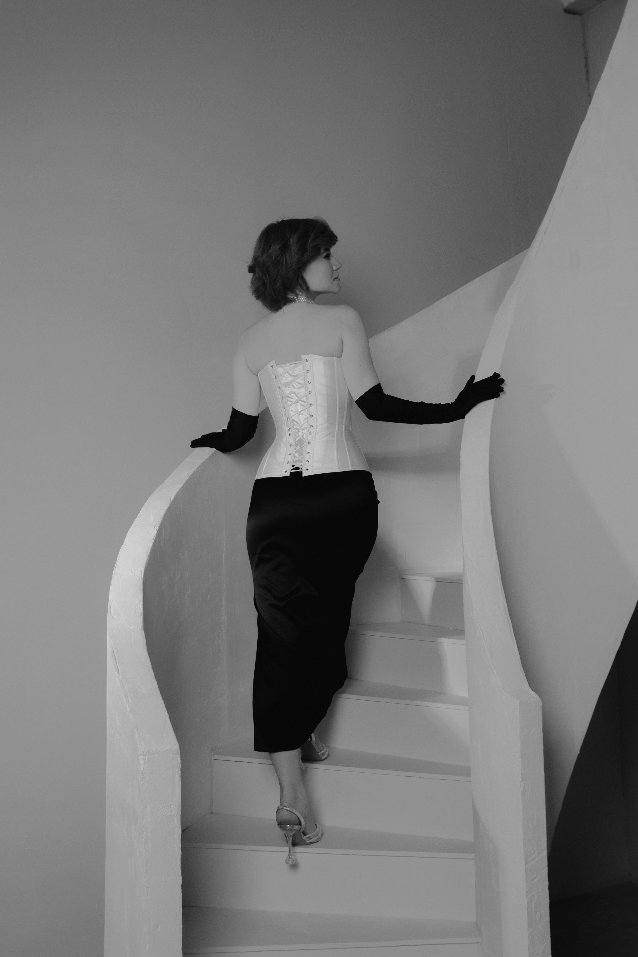 девушка на каблуках поднимается по лестнице в юбке перчатках и корсете