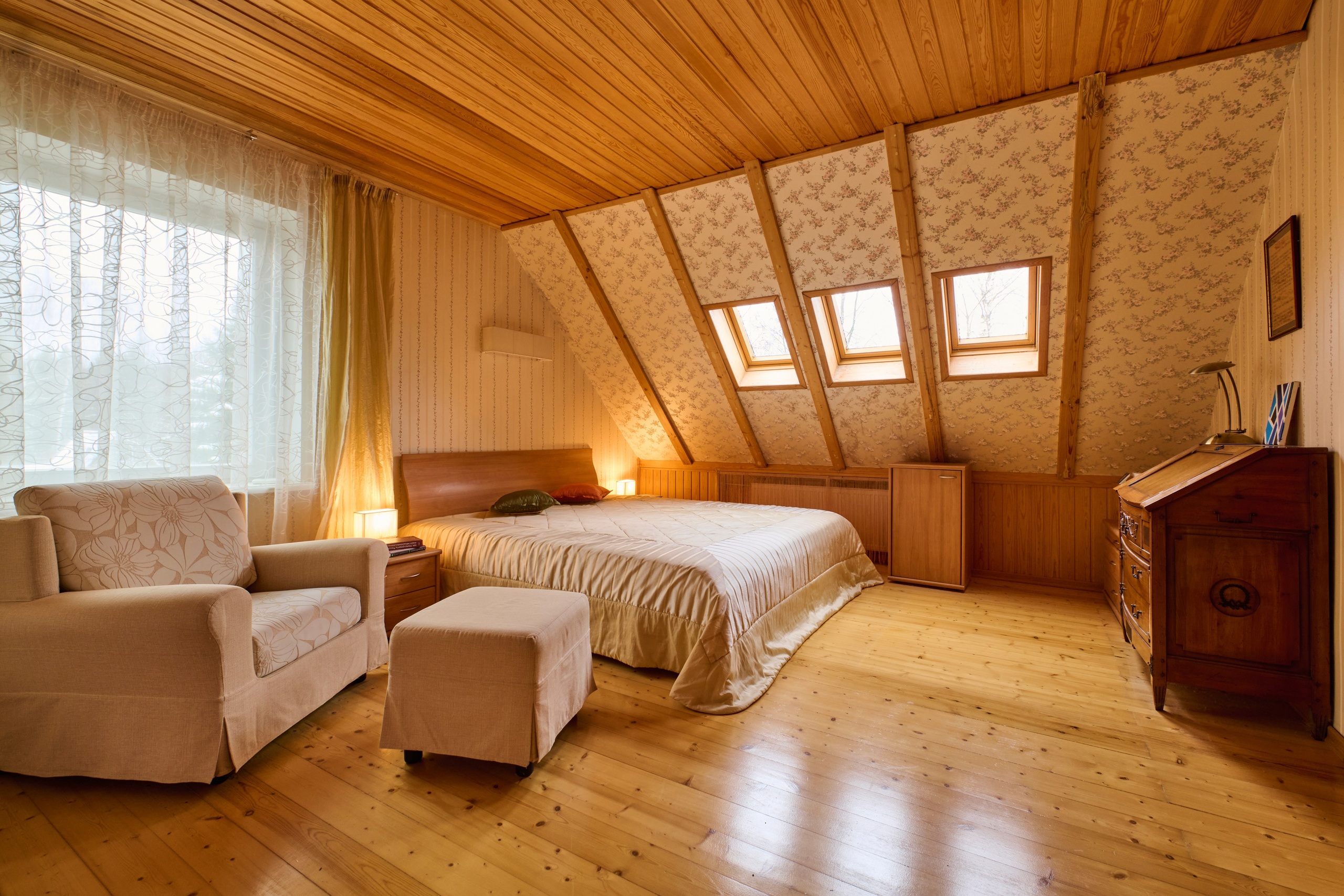 Мансардная гостиная с диваном и окнами, общий план / Гостиная под скатной крышей, светлый пол, мягкая зона