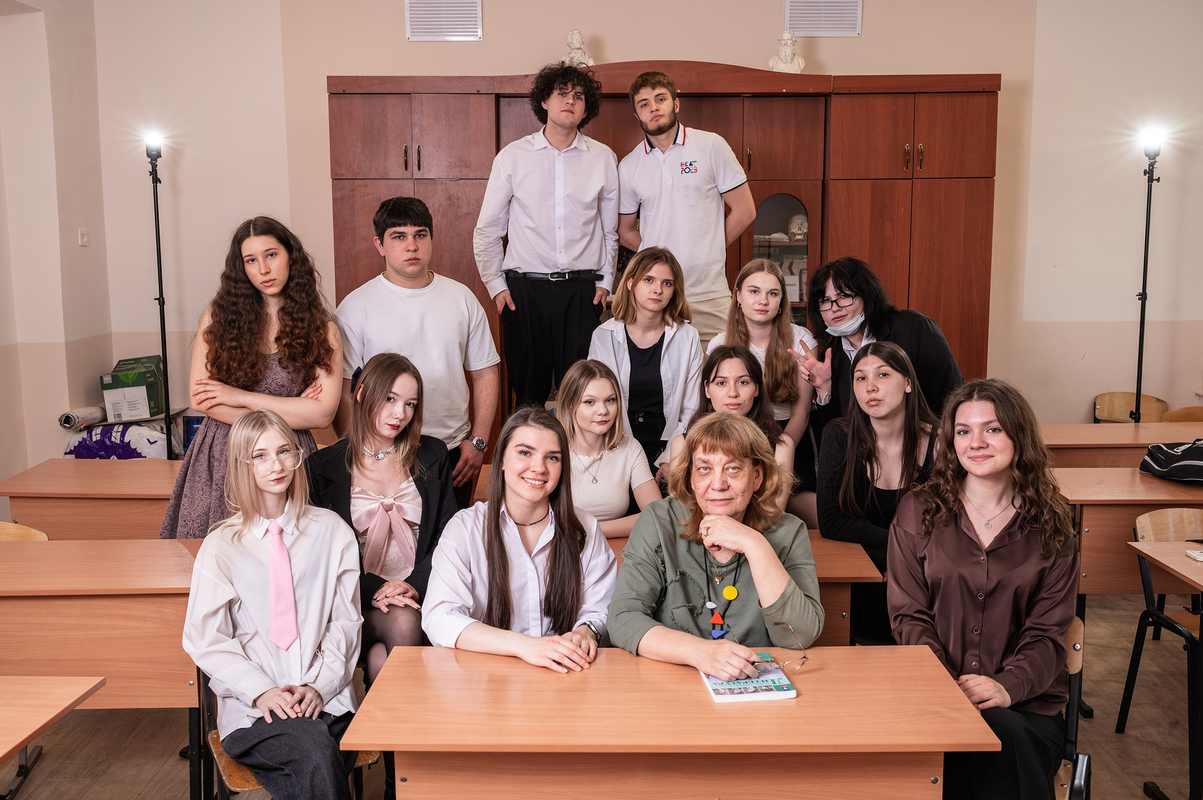 Классный руководитель с учениками позируют на фотосессии в кабинете литературы.