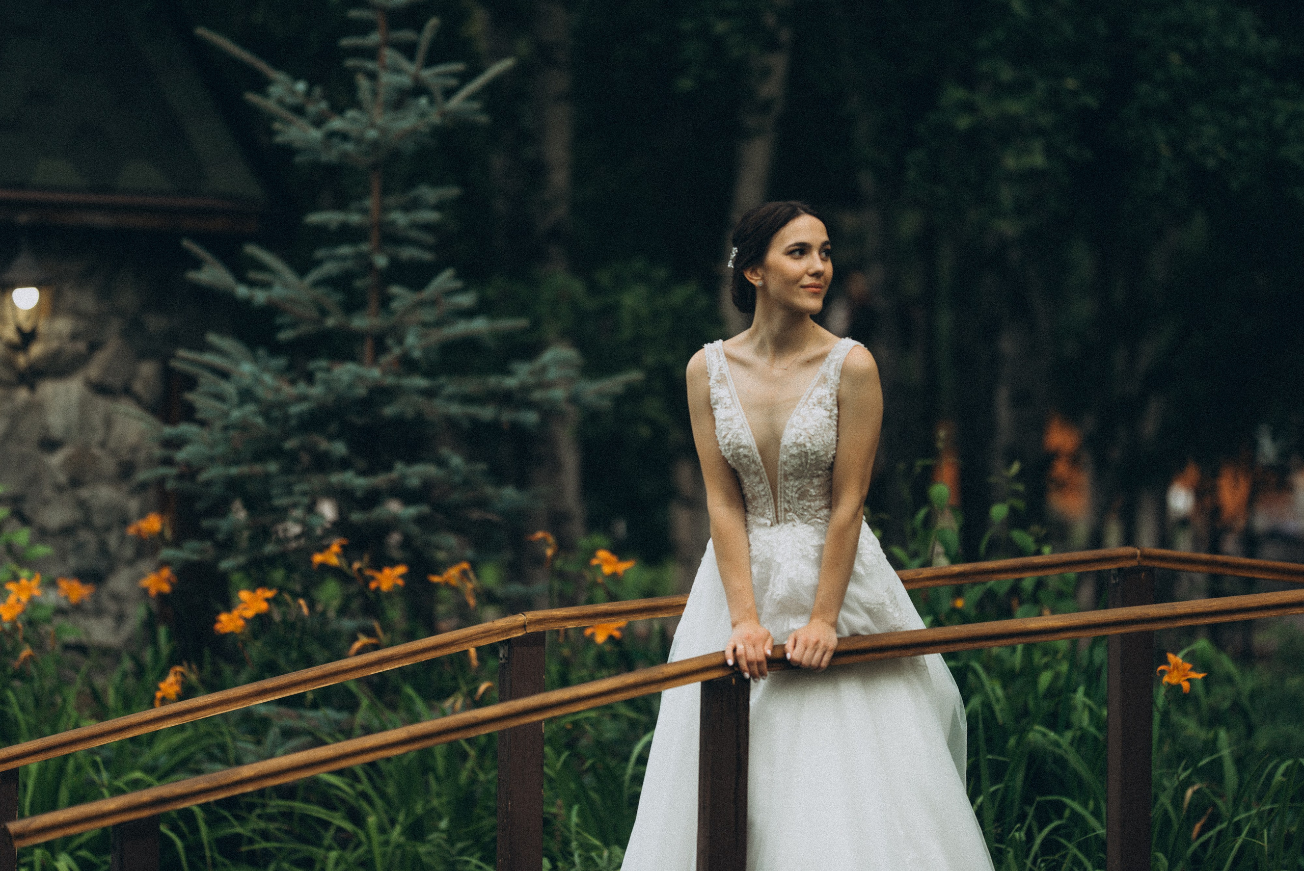 Невеста Линда в кружевном свадебном платье на деревянном мостике в загородном парке Новосибирска.