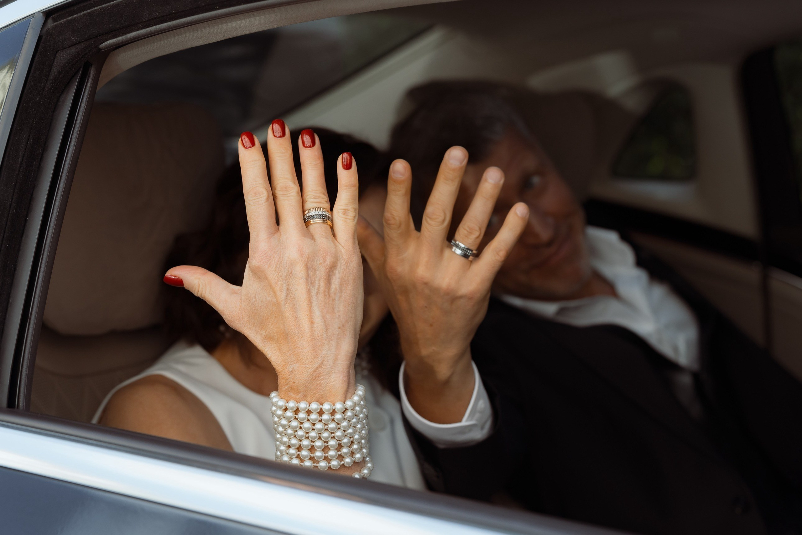 Руки молодожёнов с обручальными кольцами в свадебном автомобиле