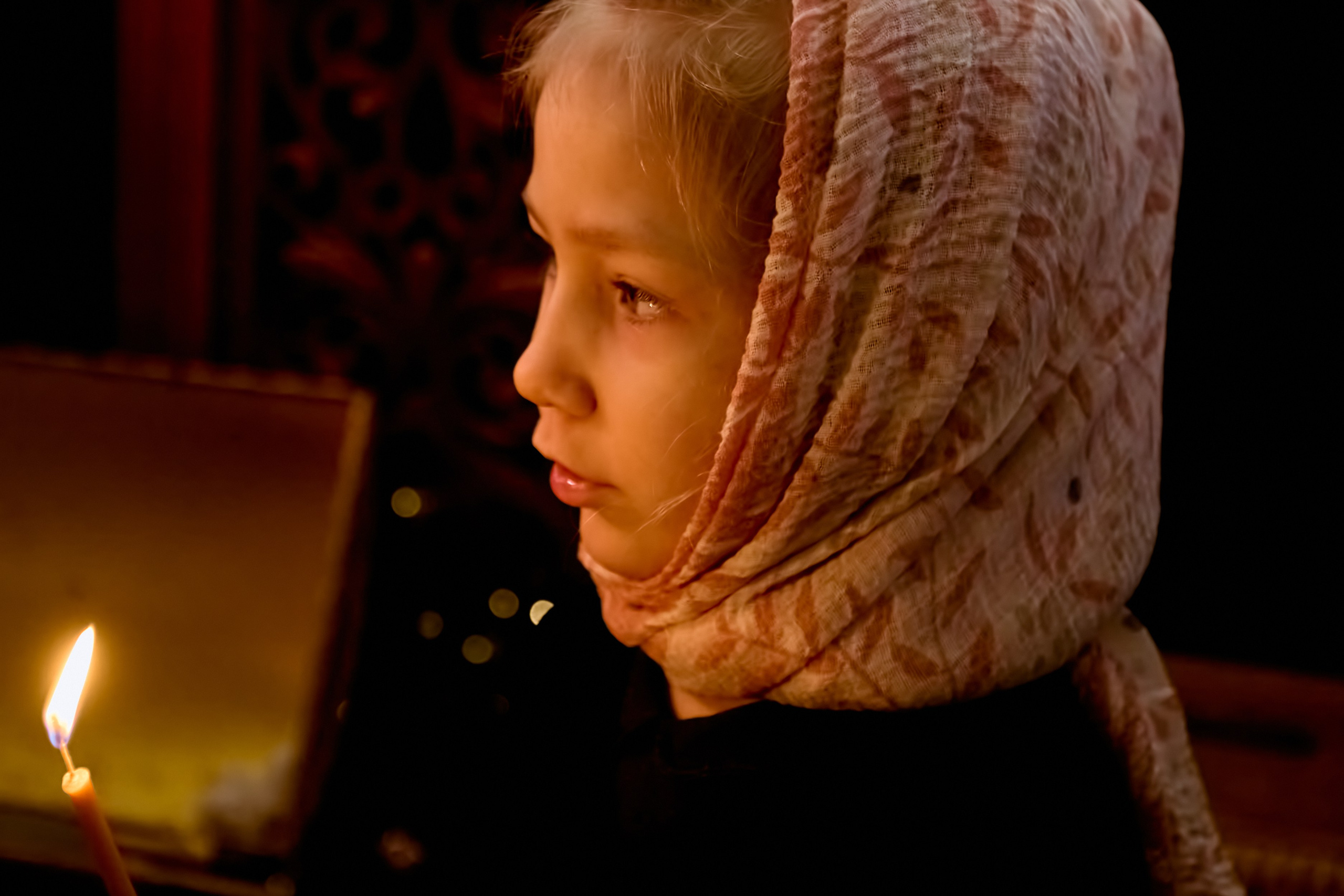 Девочка в храме держит свечку в руках