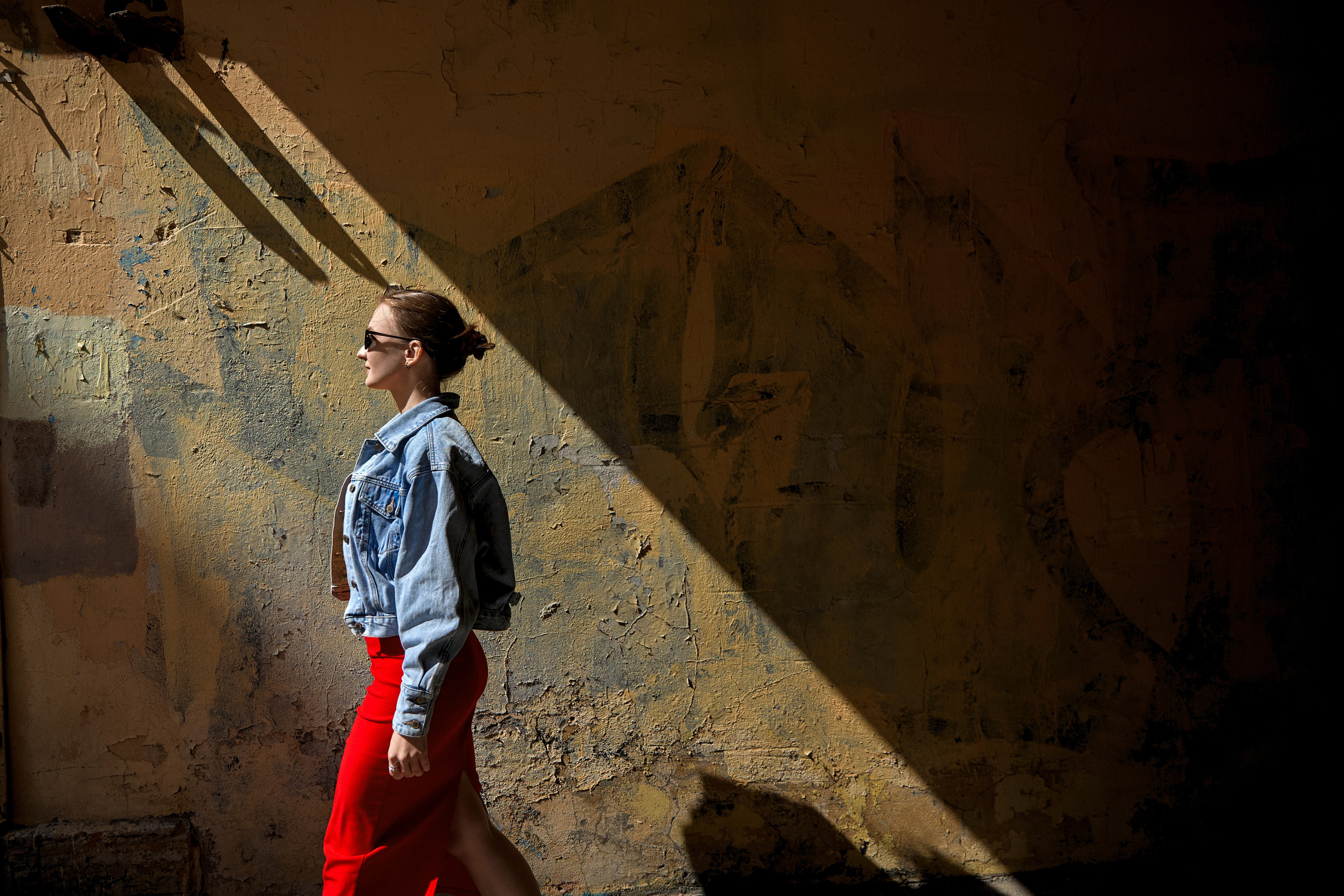 силуэт девушки выходящей в свет на фоне текстурной стены