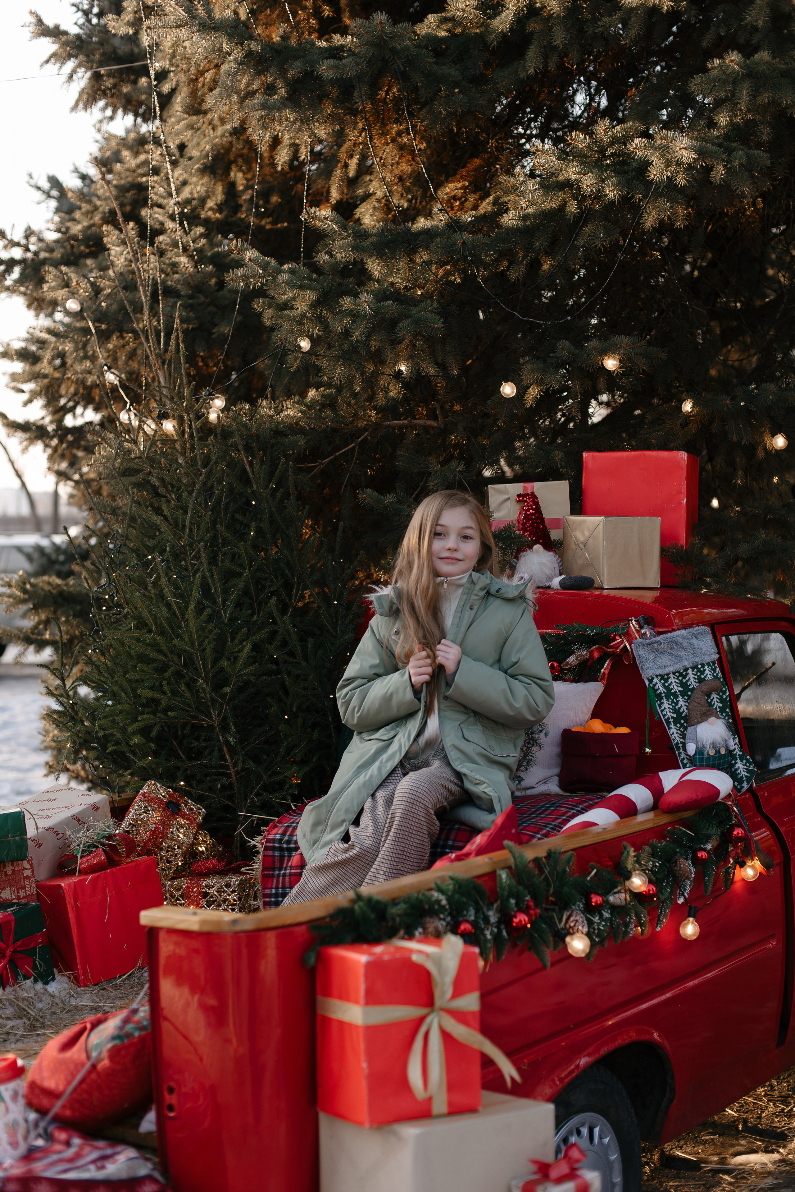 Катерина Гущина, фотограф Самара: Девочка в зеленой куртке сидит на фоне новогодней елки.