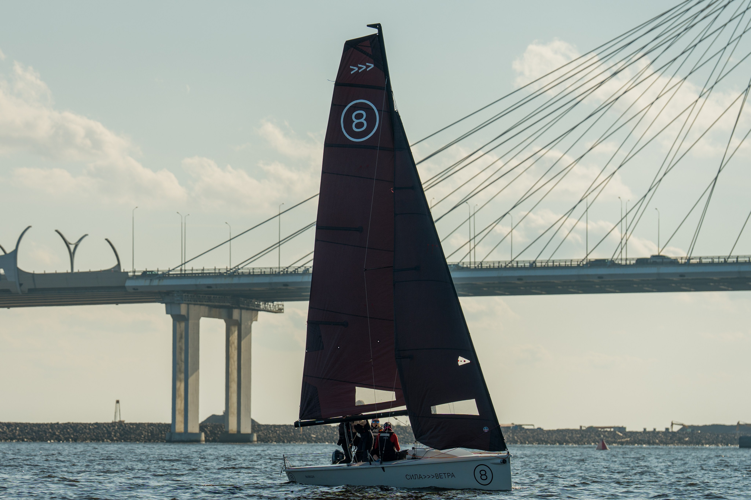 SV20 crew sails under a dark mainsail near Lakhta Center