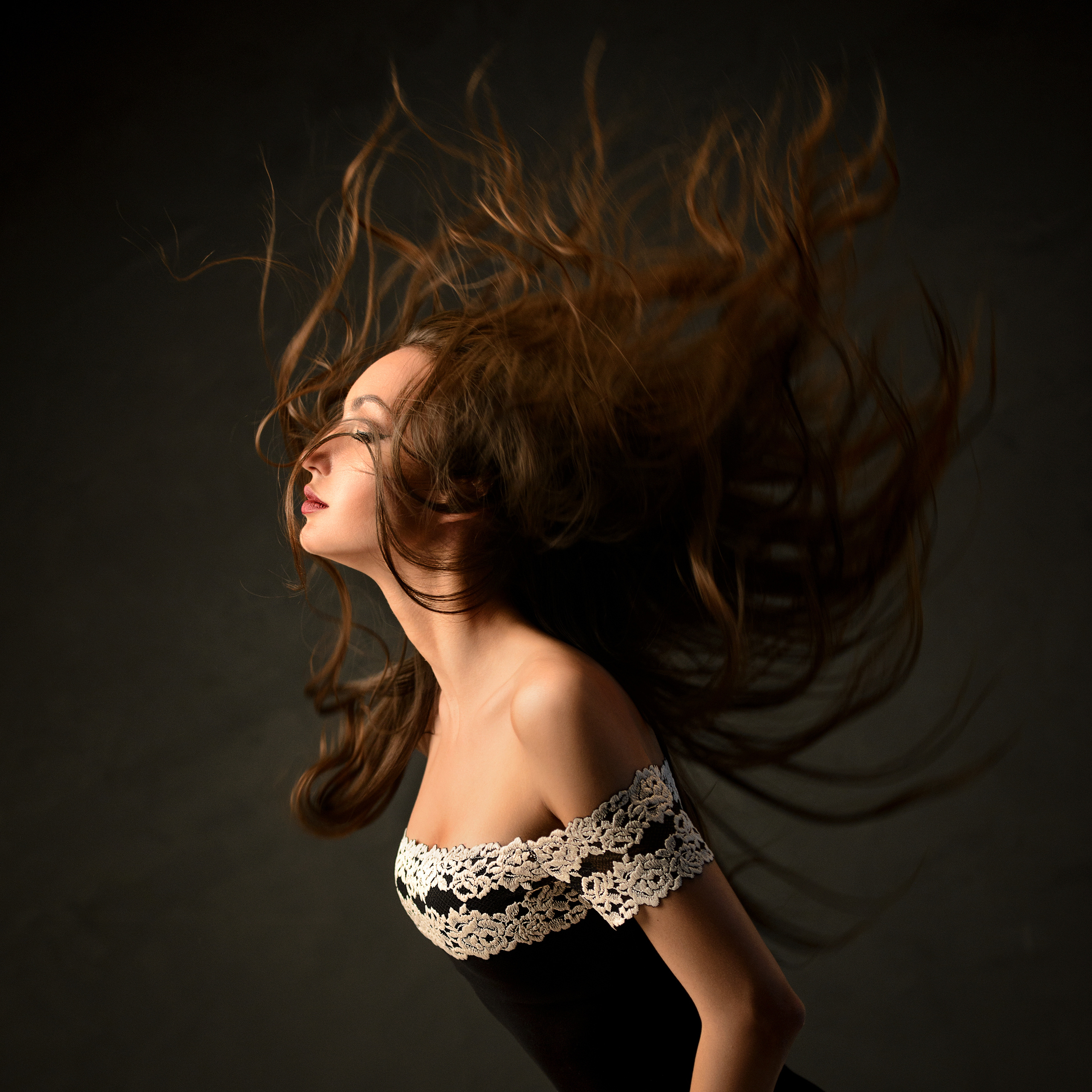 Студийный портрет, девушка с летящими волосами в красивом боди на сером фоне