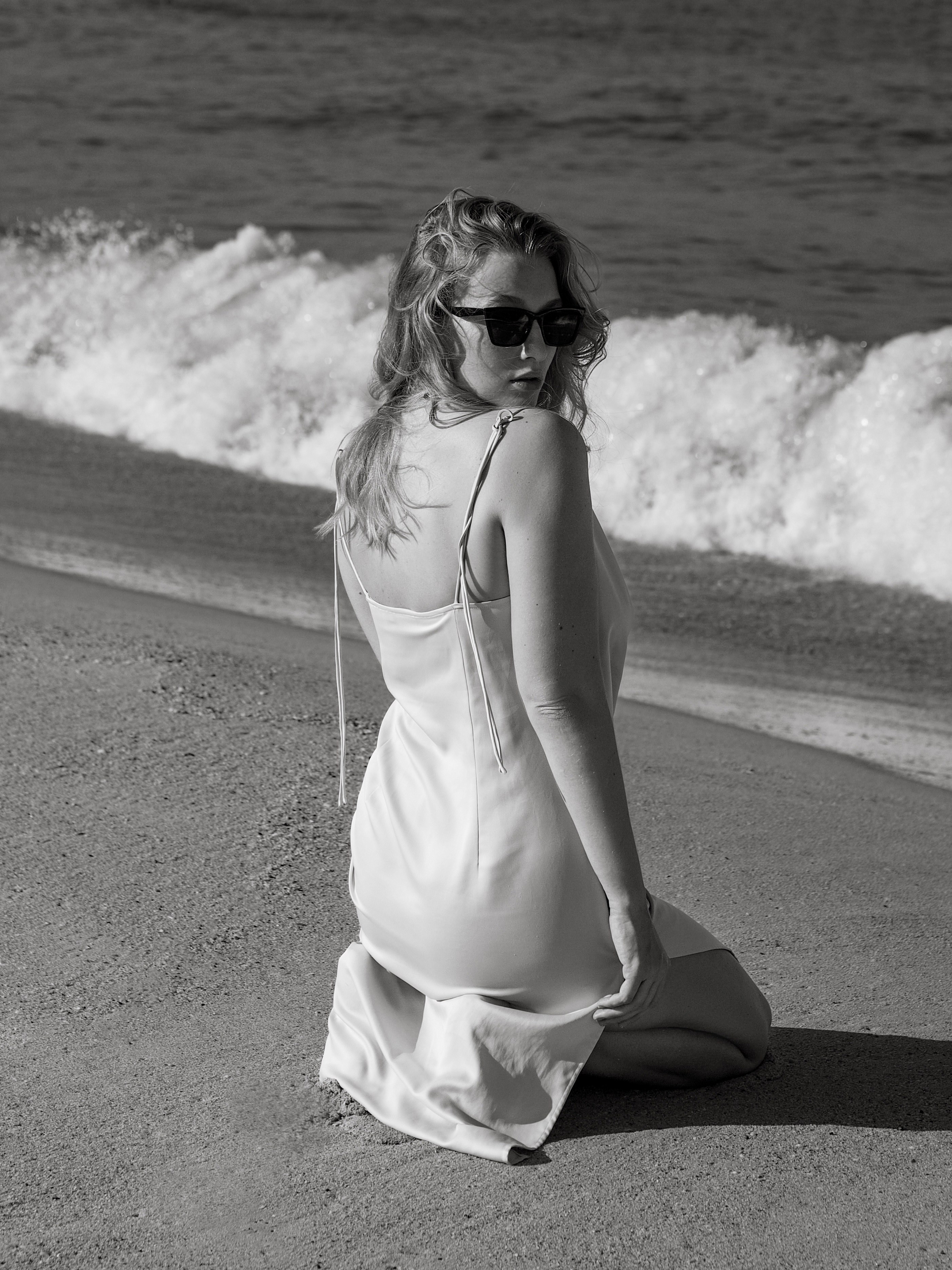Модная фотография девушки на пляже в черно-белом фильтре.
