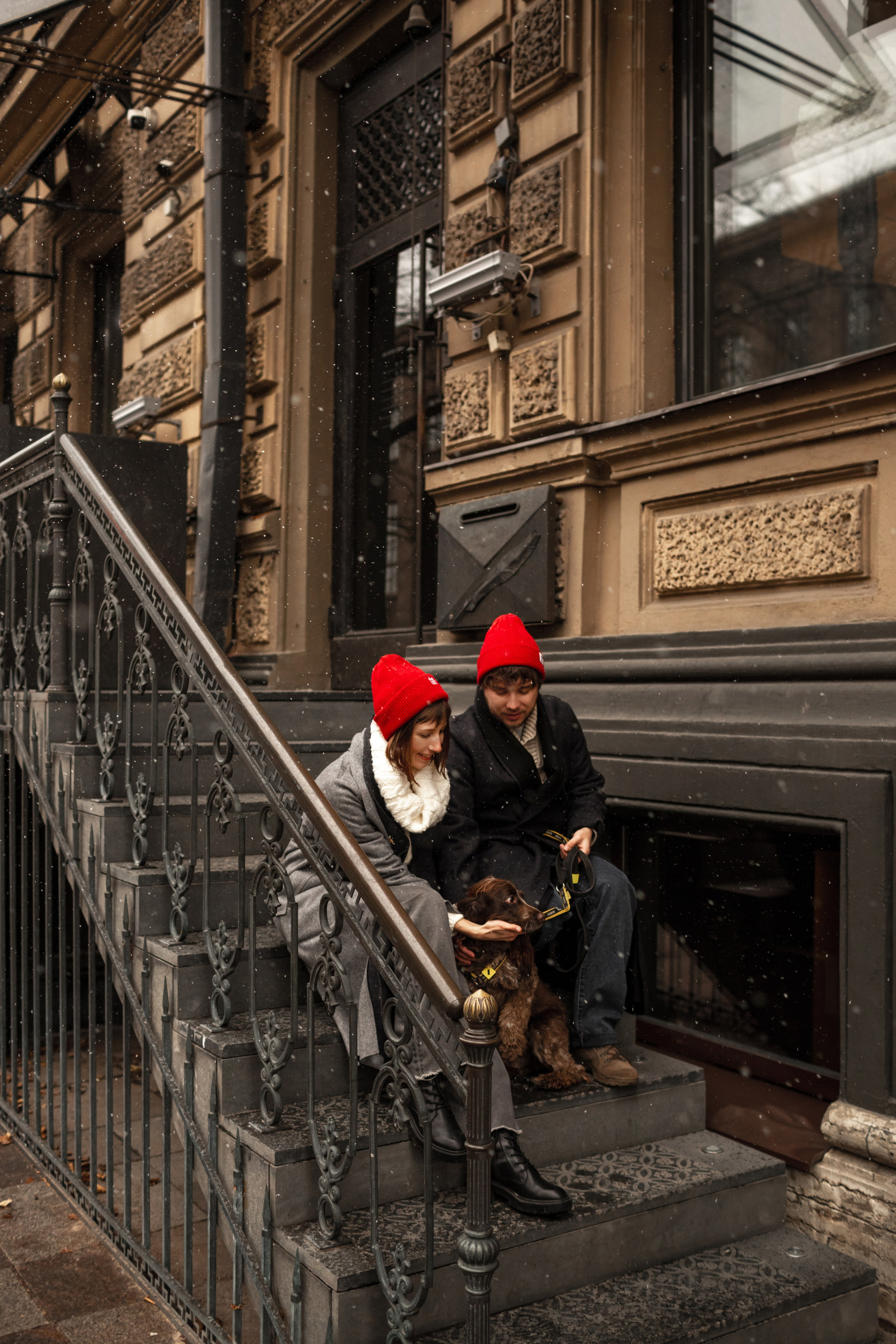 Семья на фотосессии с собакой сидит на ступенях исторического здания.