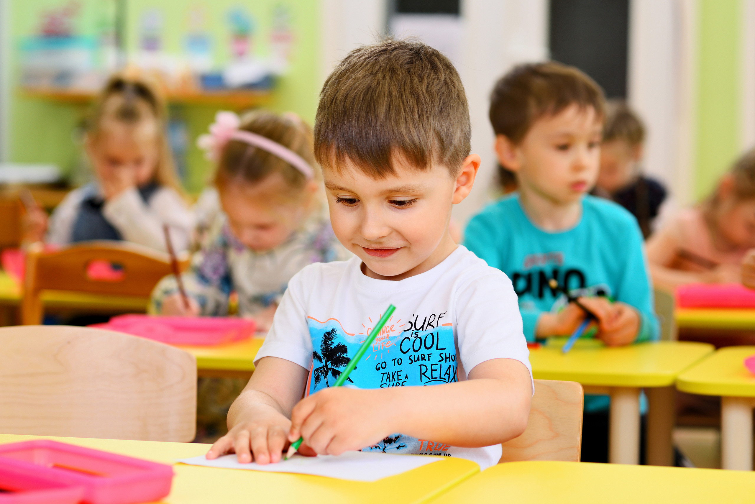  Мальчик рисует карандашами на занятии в детском саду.