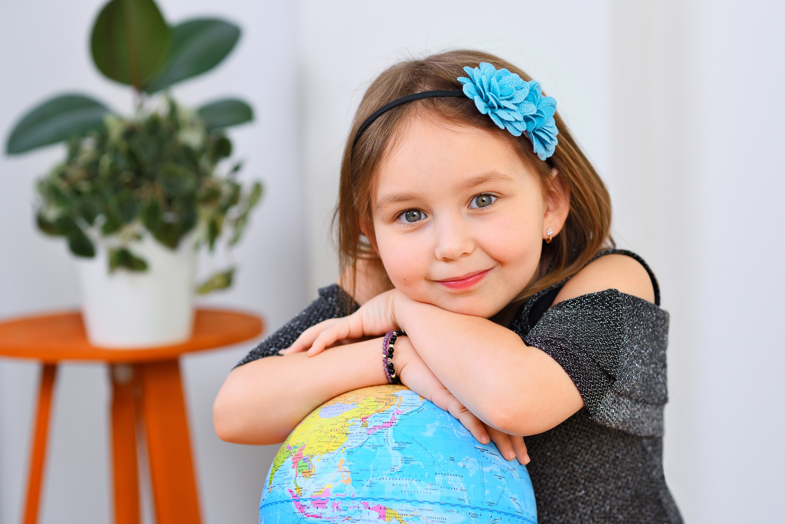 Девочка в детском саду обнимает глобус.