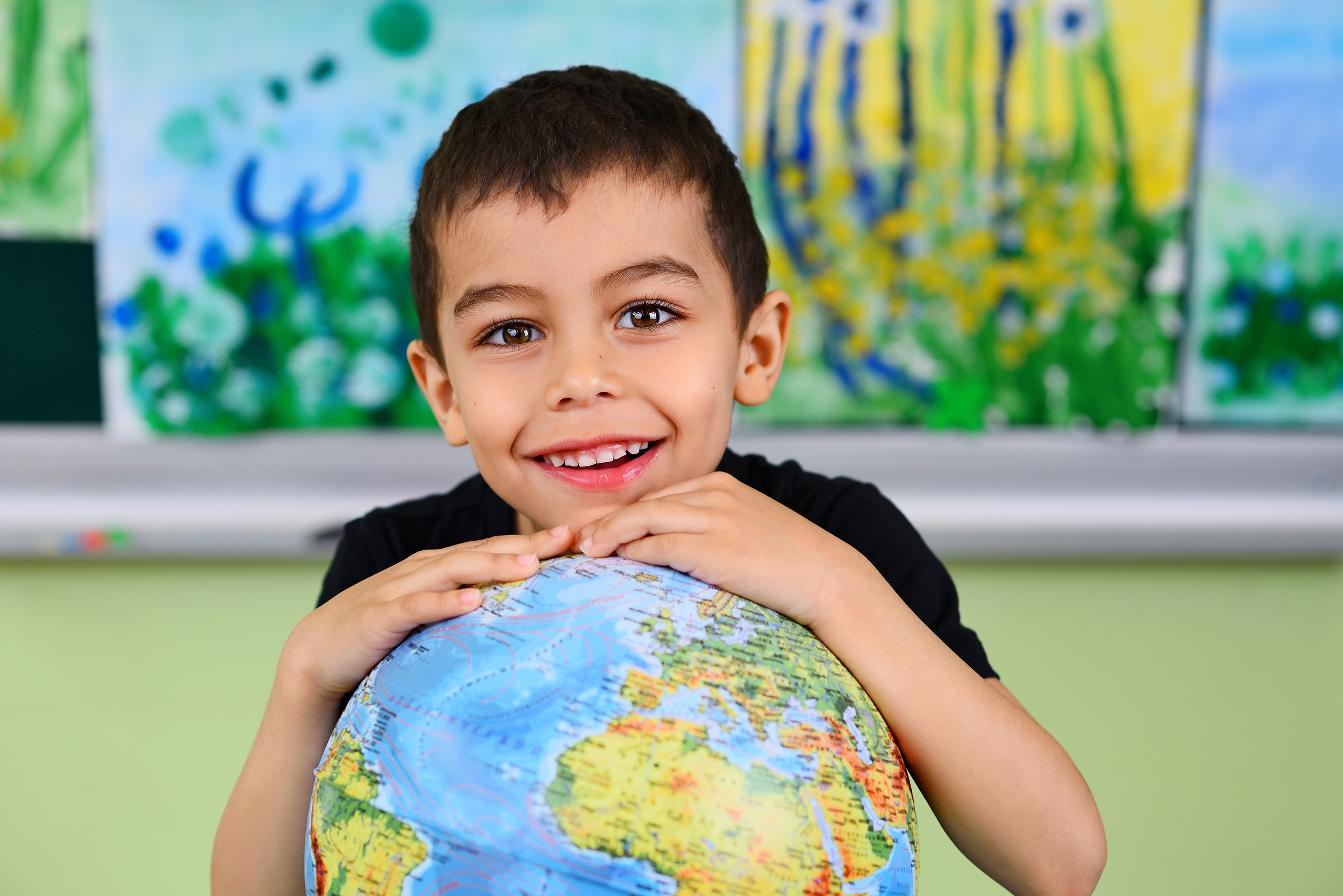 Портрет мальчика в детском саду в обнимку с глобусом.