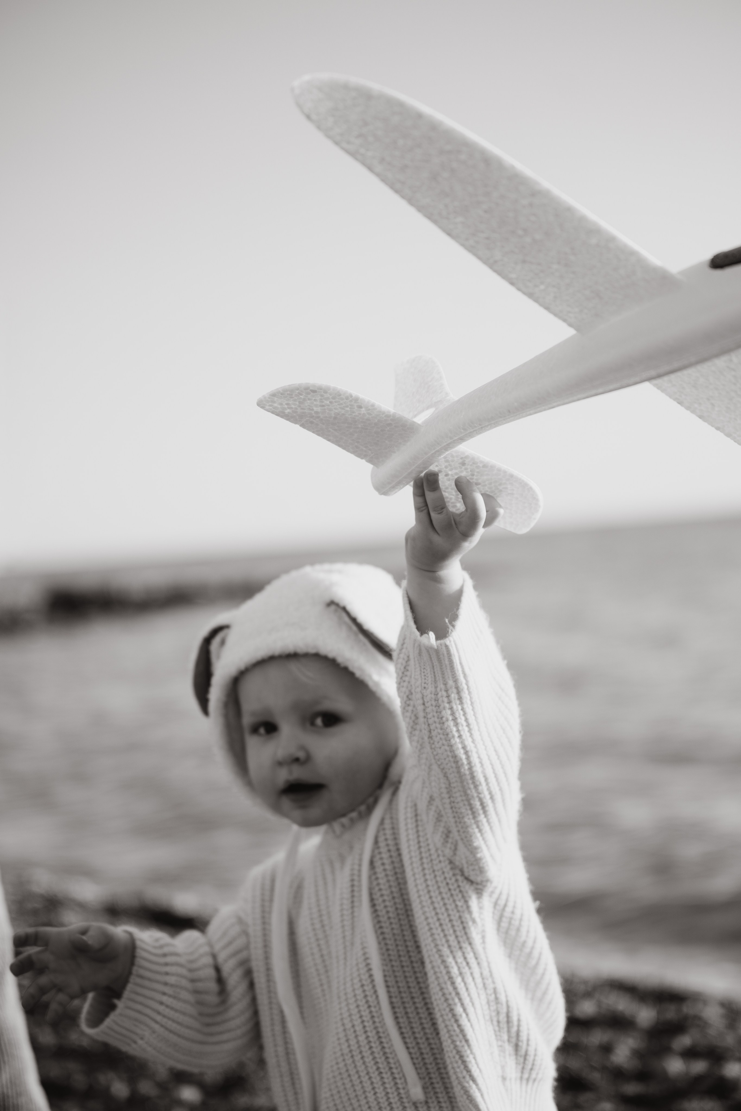 Романтический портрет родителей на фоне моря. Дети остаются на заднем плане, играя у кромки воды. Фотосессия в Новороссийске у моря.