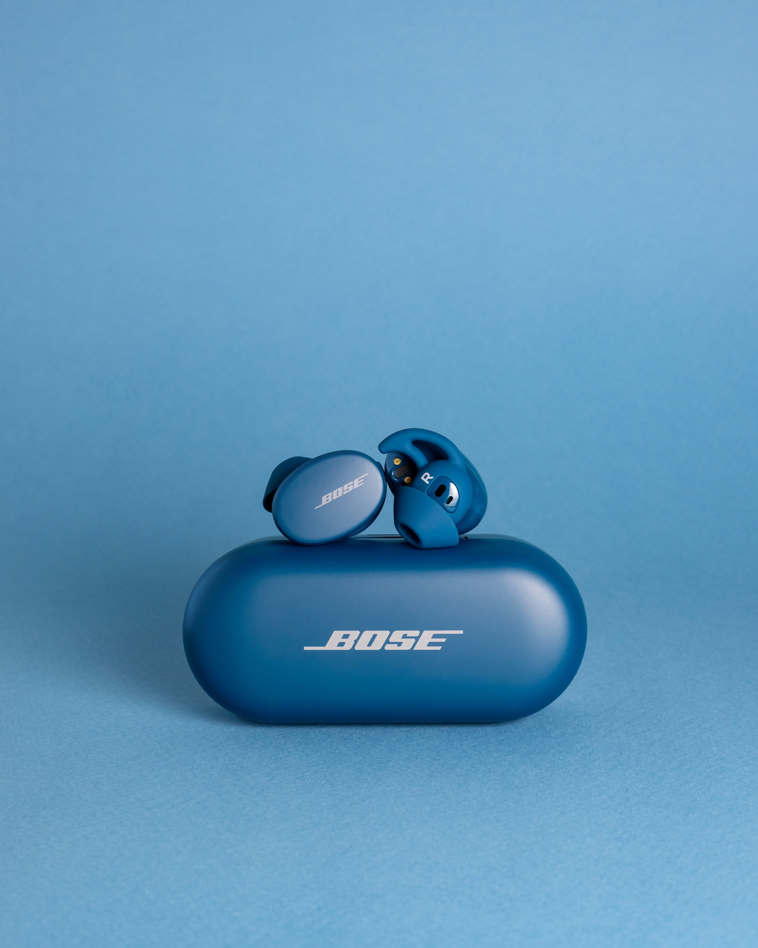 Спортивные беспроводные внутриканальные наушники Bose Sport Earbuds цвета Baltic Blue на синем фоне.