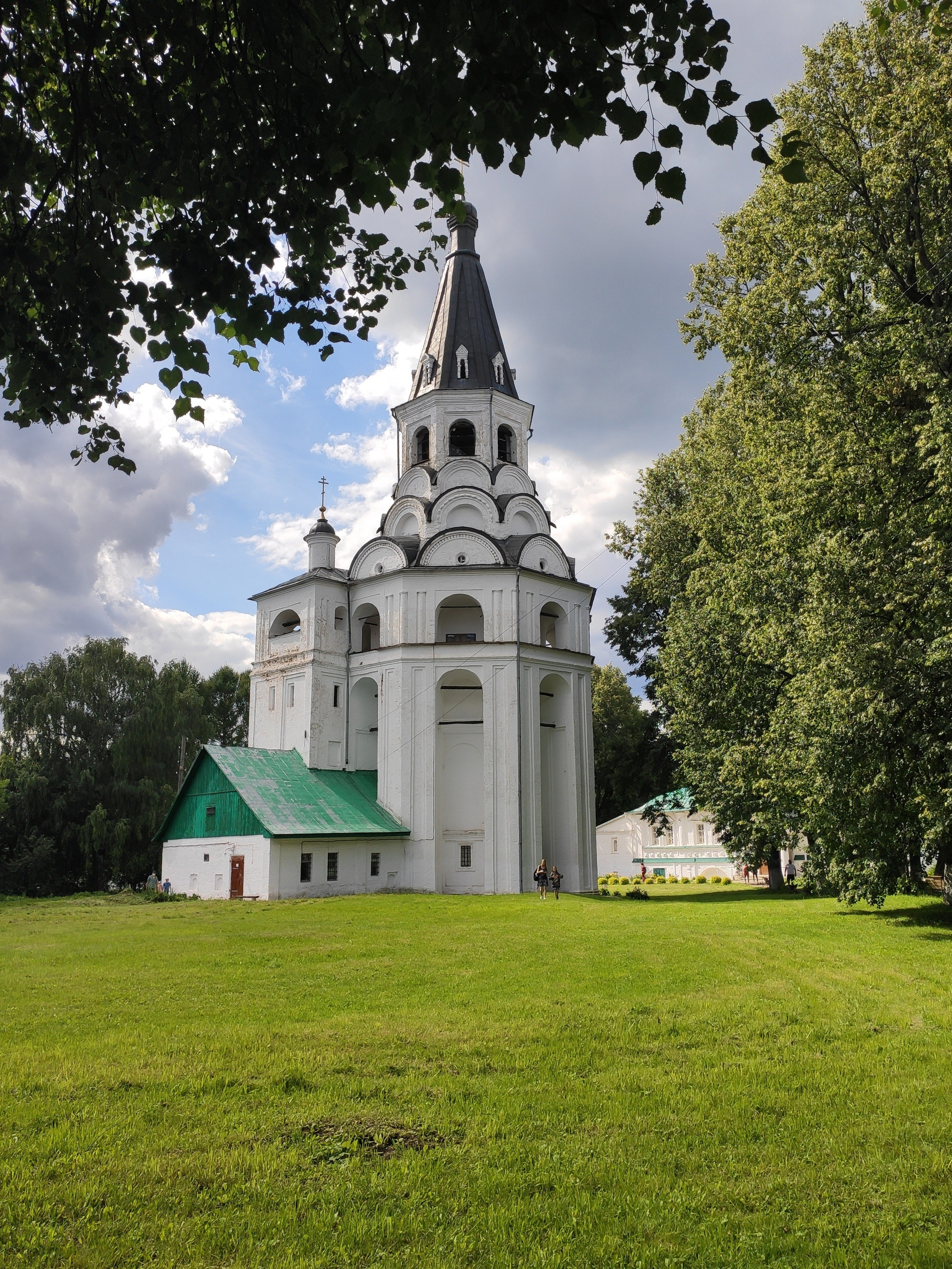Колокольня выделяется белизной на зеленой лужайке