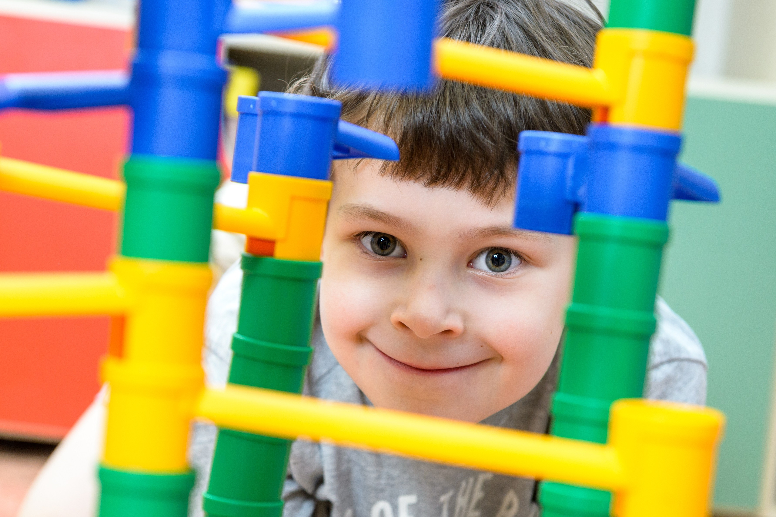 Мальчик выглядывает из цветного конструктора, лицо в рамке из деталей.