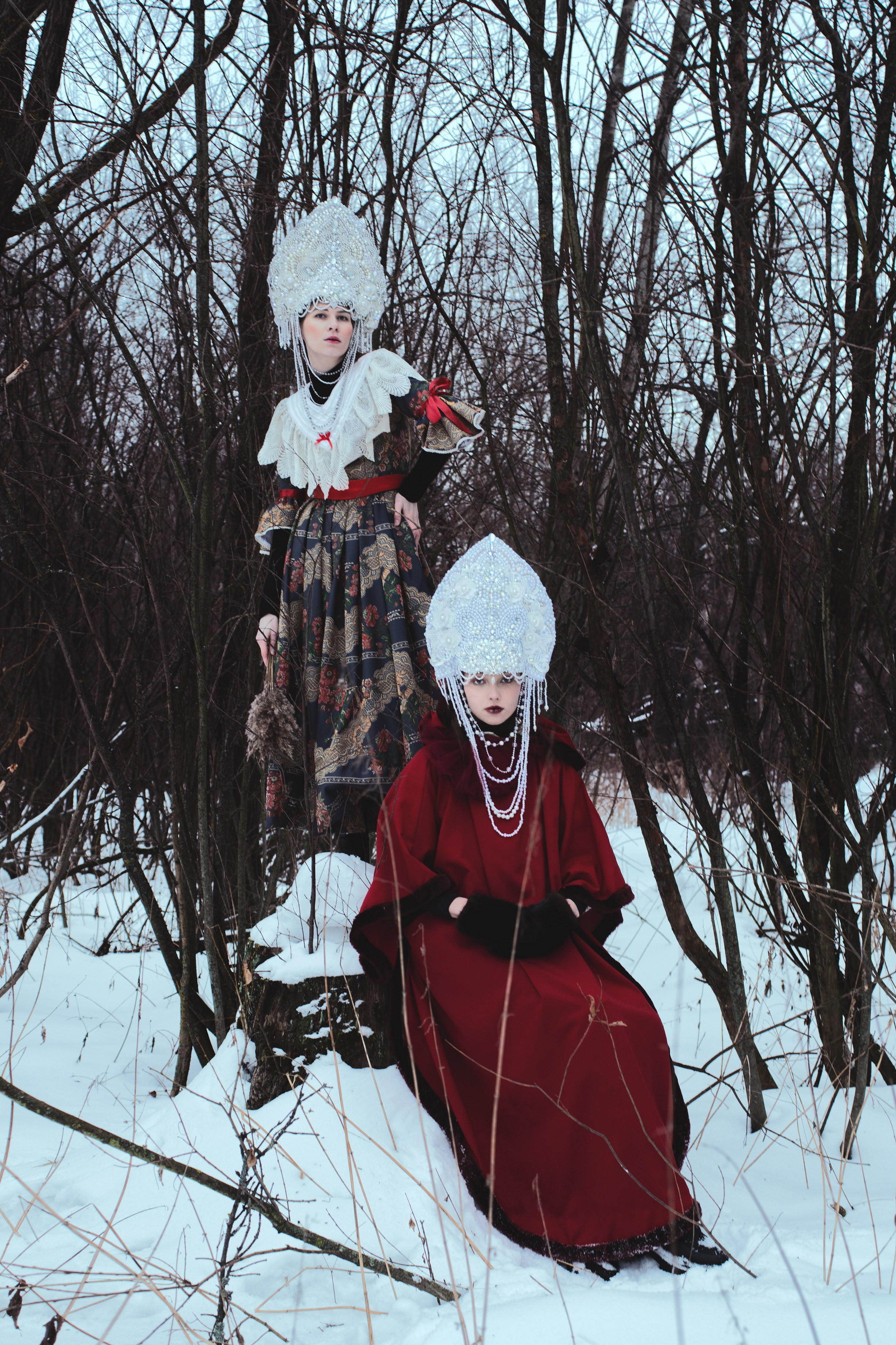 Две девушки в лесу зимой в русских народных костюмах на масленицу 