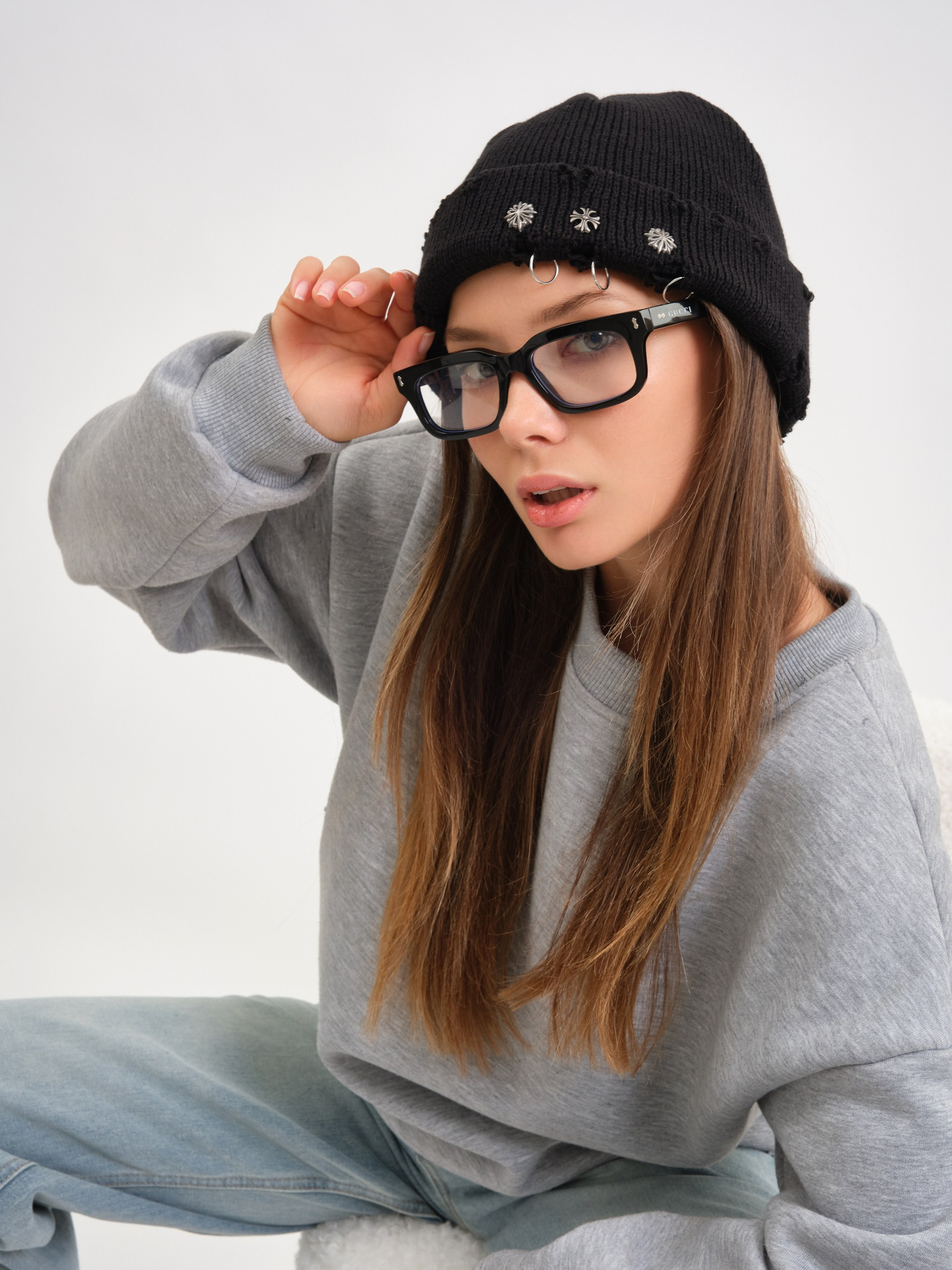 Модель в очках и свитере, поза сидя