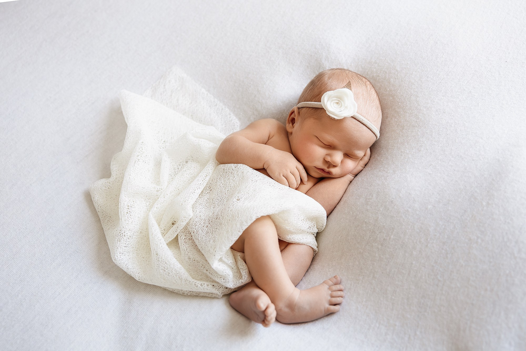 Крупный план: новорожденный ребенок сладко спит, подложив ручку под щёчку.