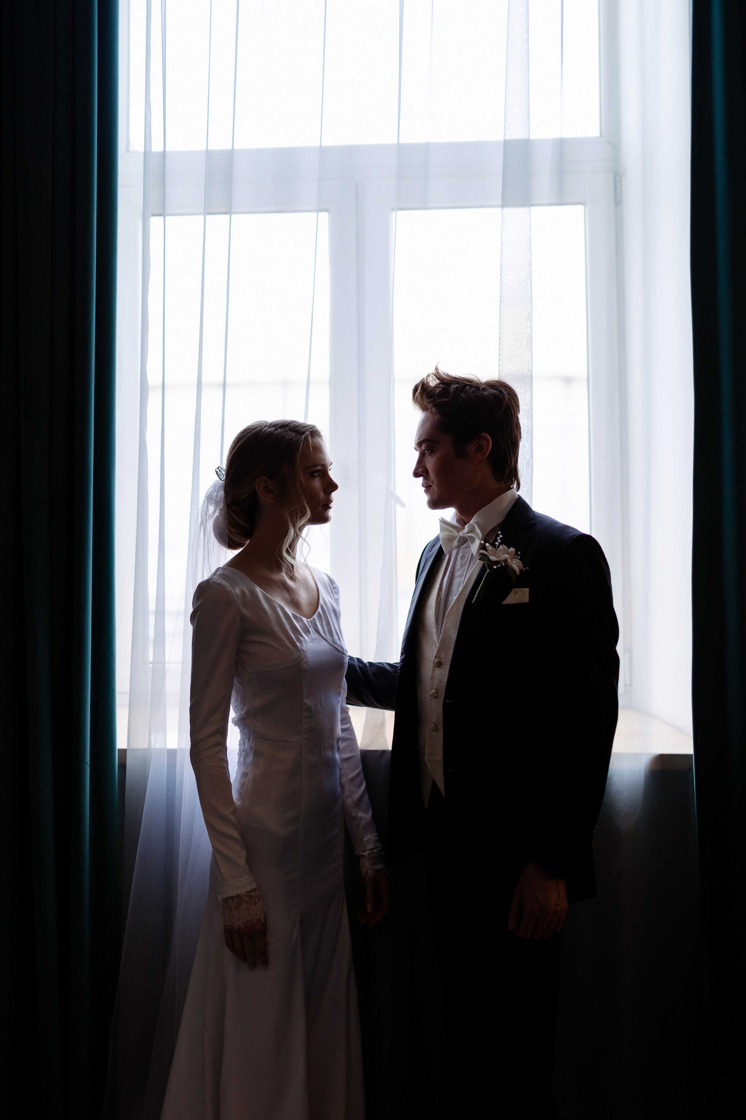 Невеста с женихом стоят у большого окна.