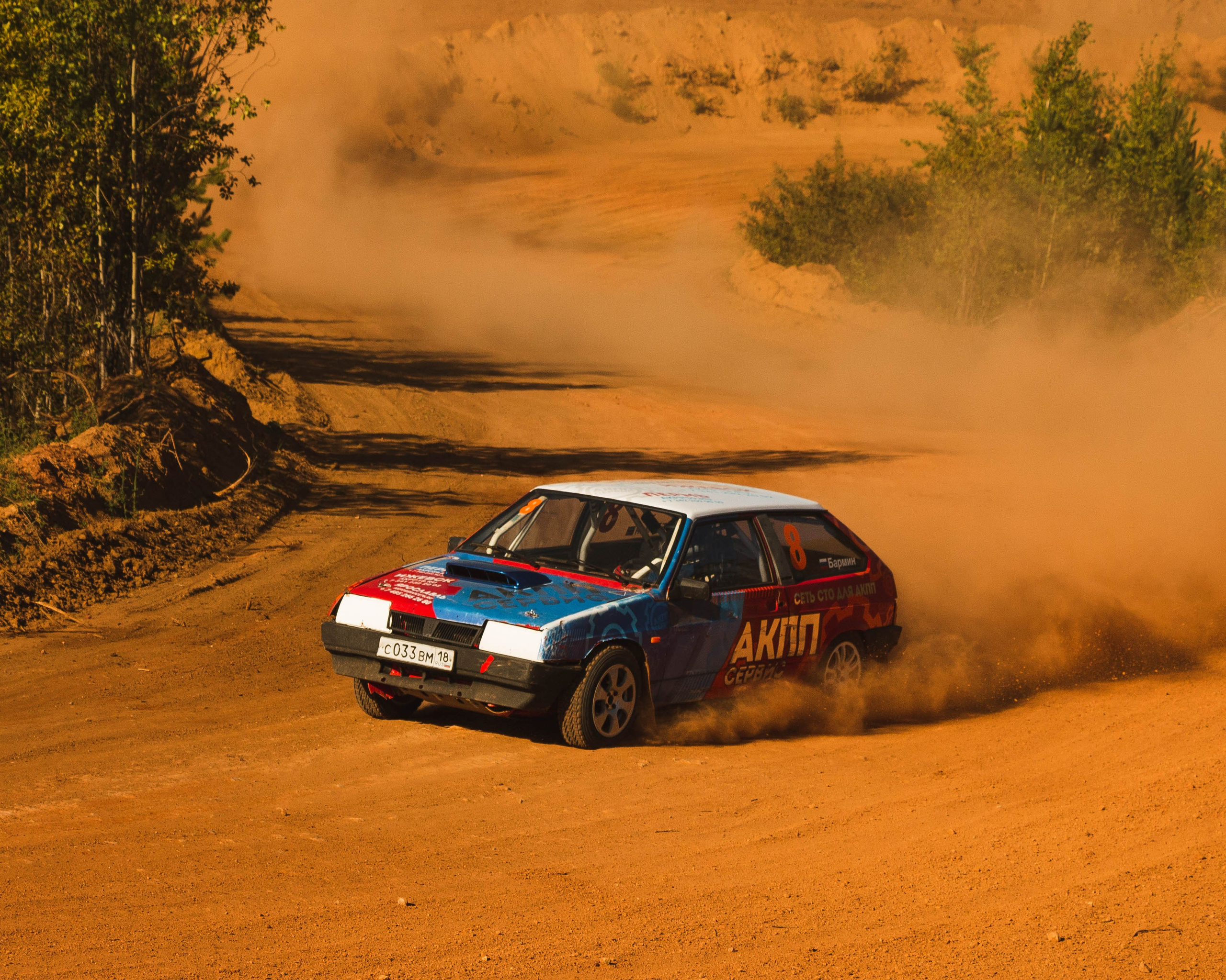 Автомобиль входит в крутой поворот на гоночной грунтовой трассе
