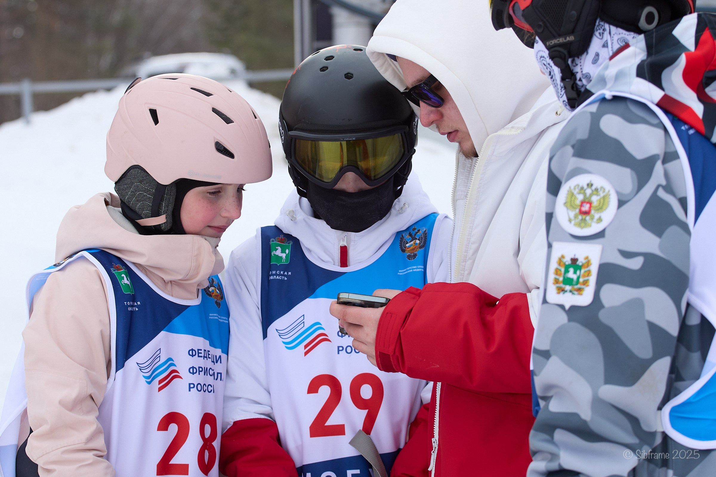 Спортсмены и тренер оценивают попытку снятую на телефон, фристайл.