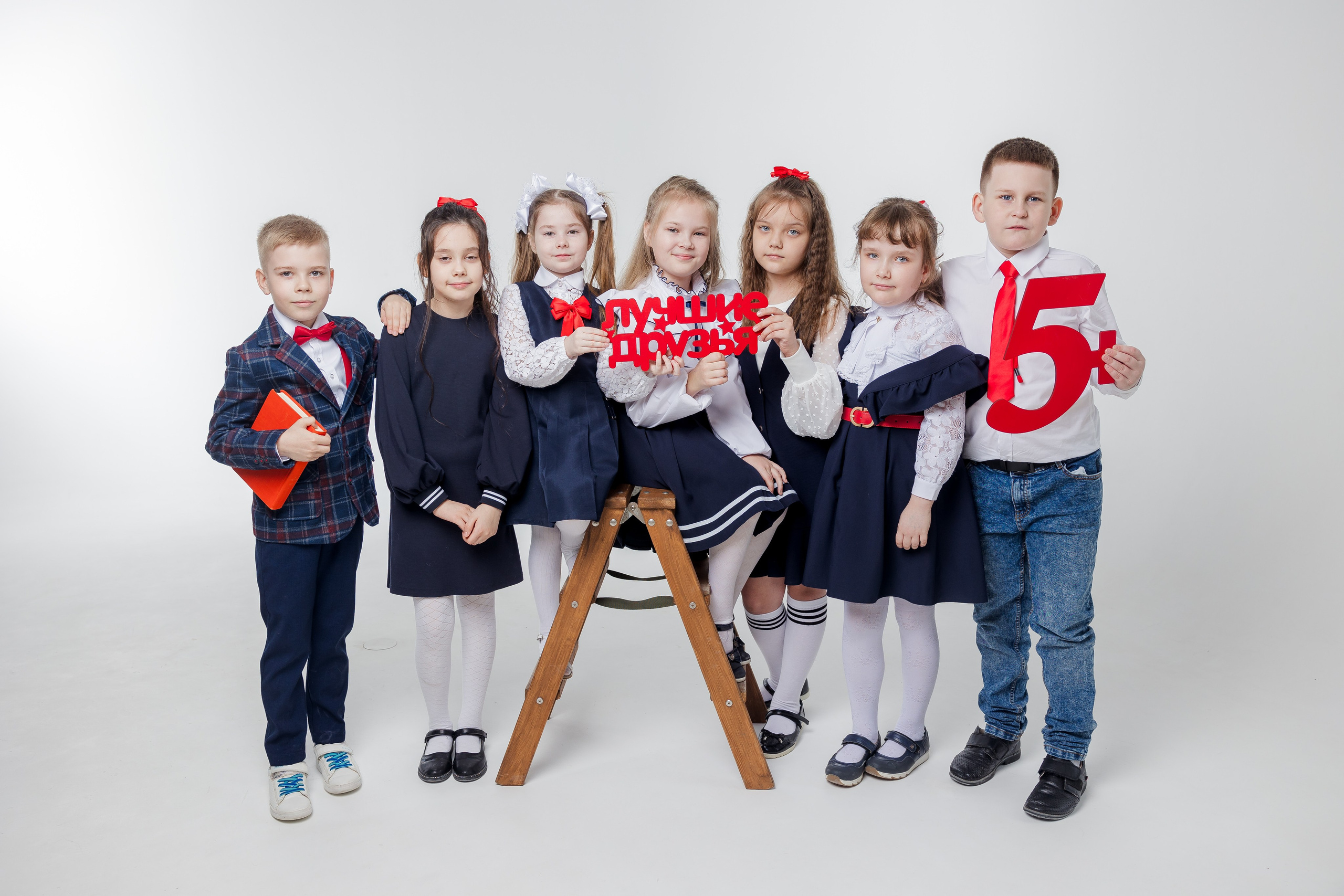 Мальчики и девочки стоят вместе в студии в одежде с красными акцентами и надписью лучшие друзья