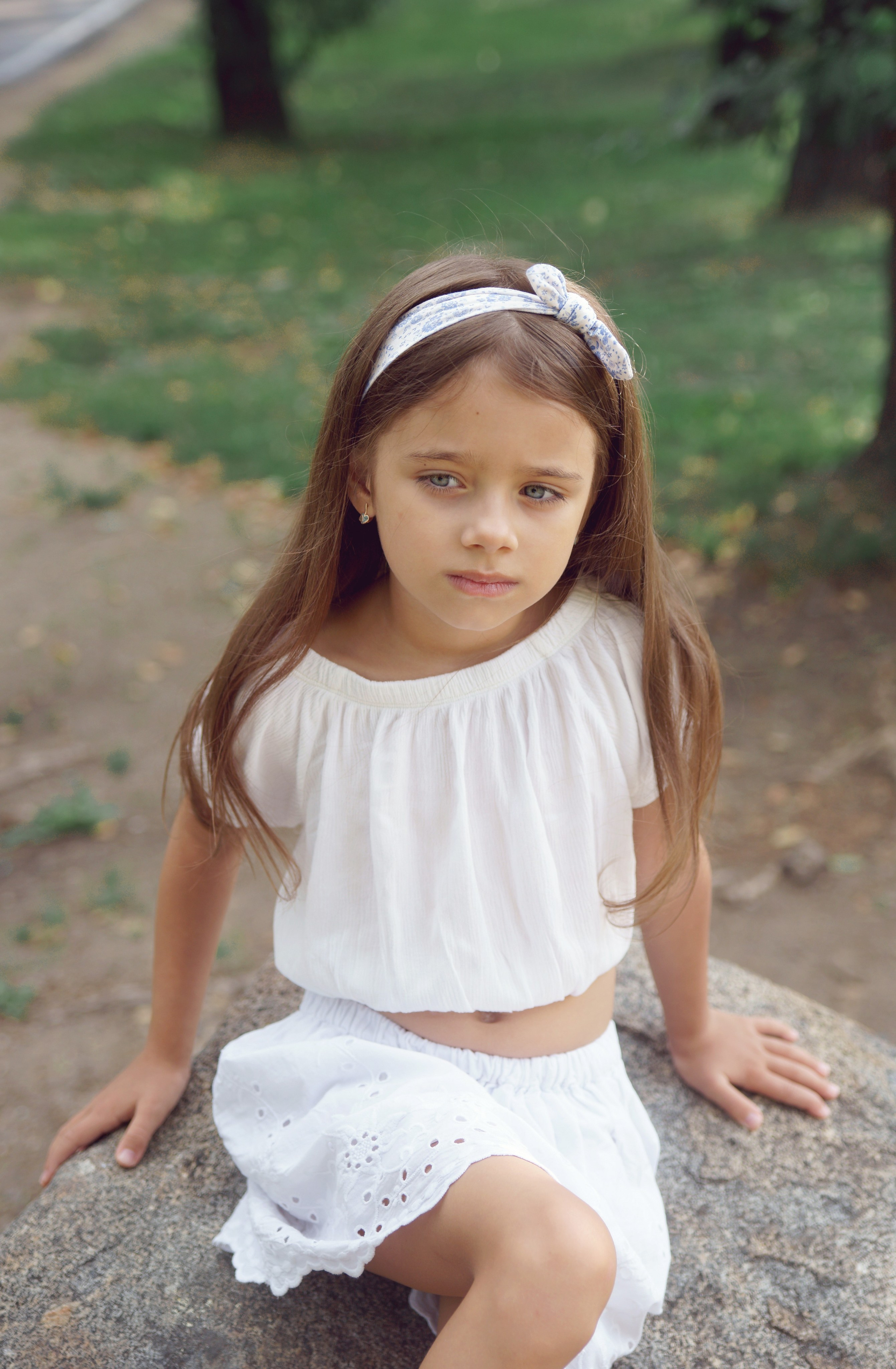 Детская фотосессия летом - девочка сидя на камне крупный портрет