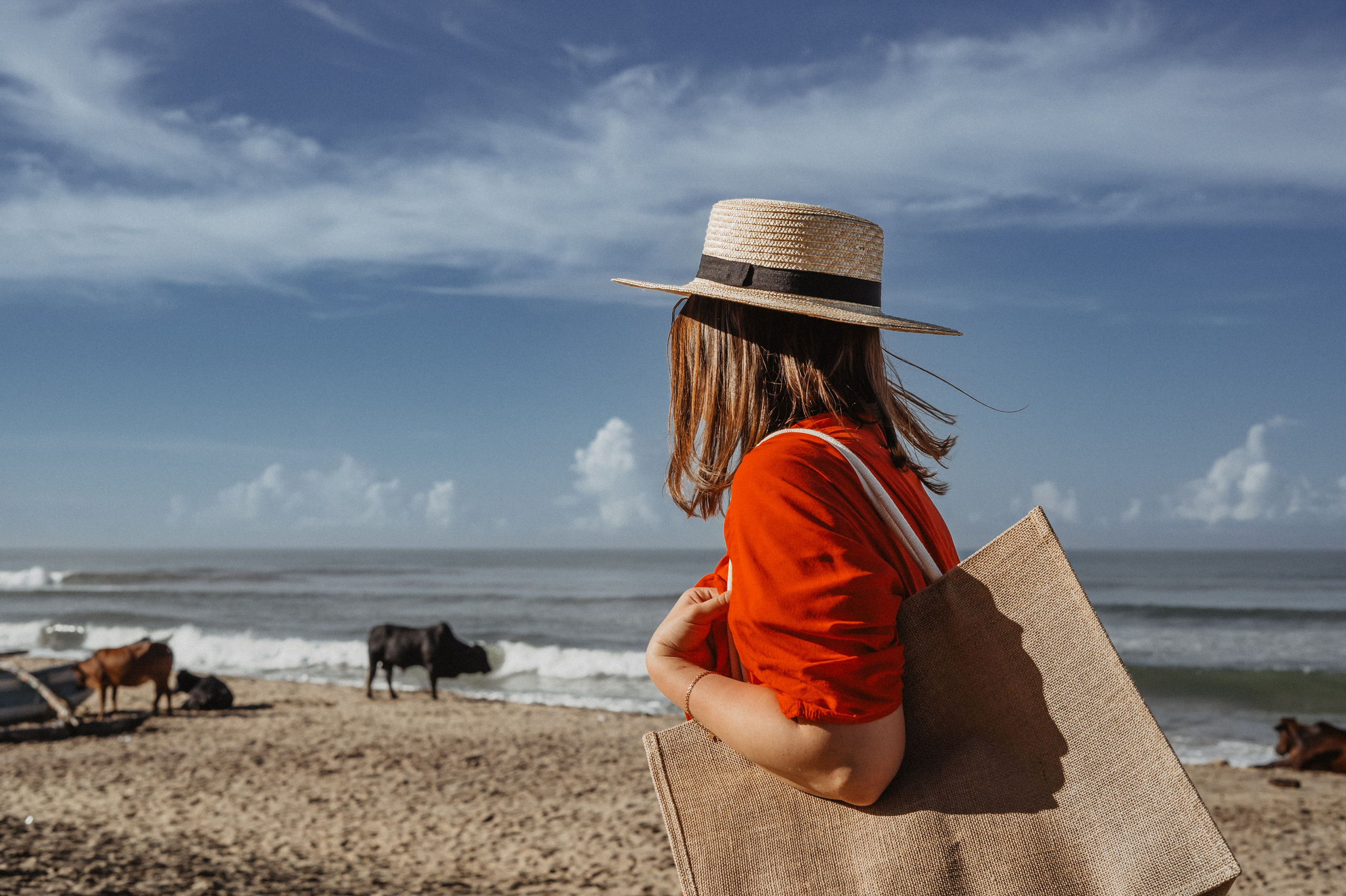 a girl in a straw hat taking steps on the sandy beach