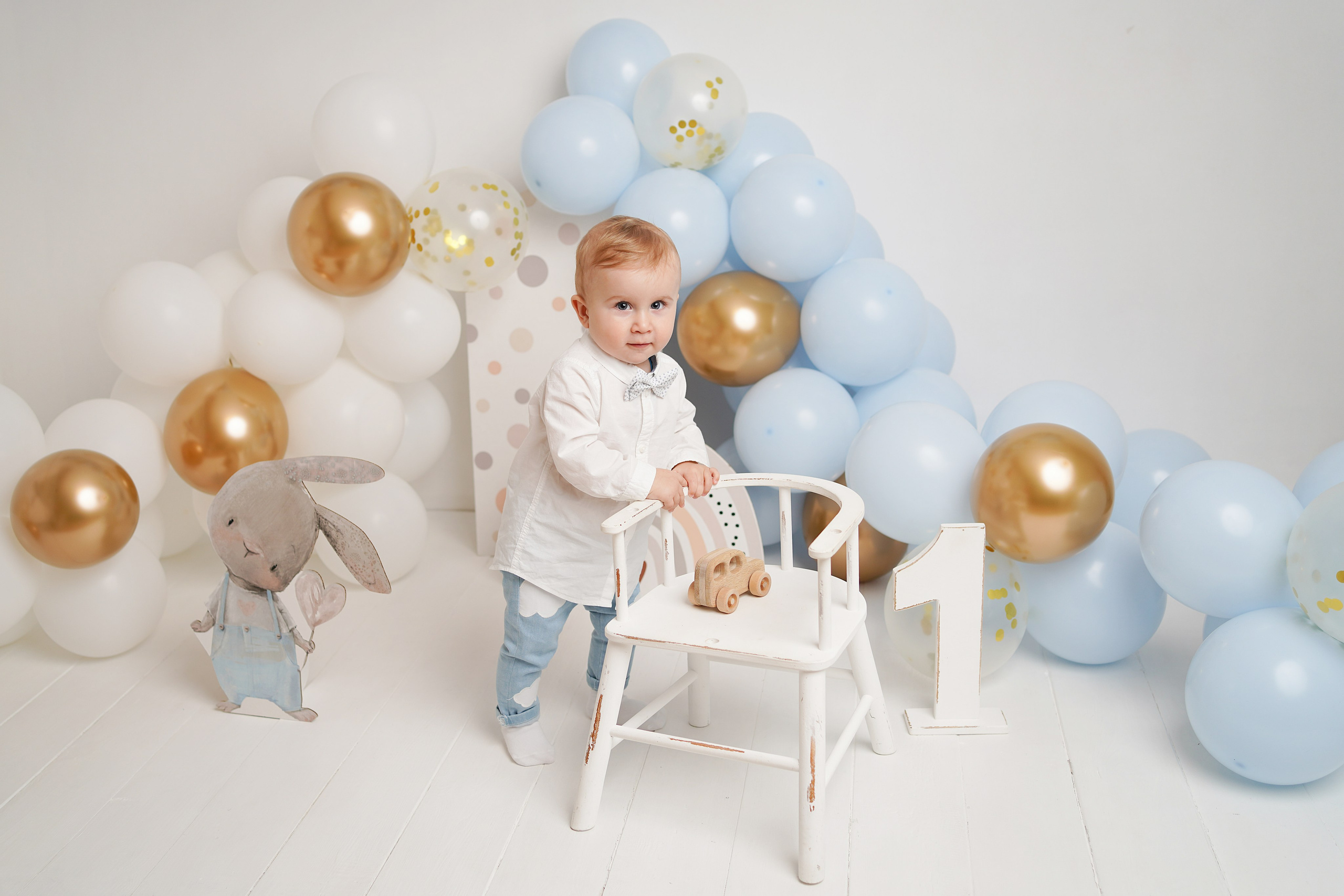 На фото малыш,  воздушные шары  в голубой цветовой гамме и атрибуты Первого годика.