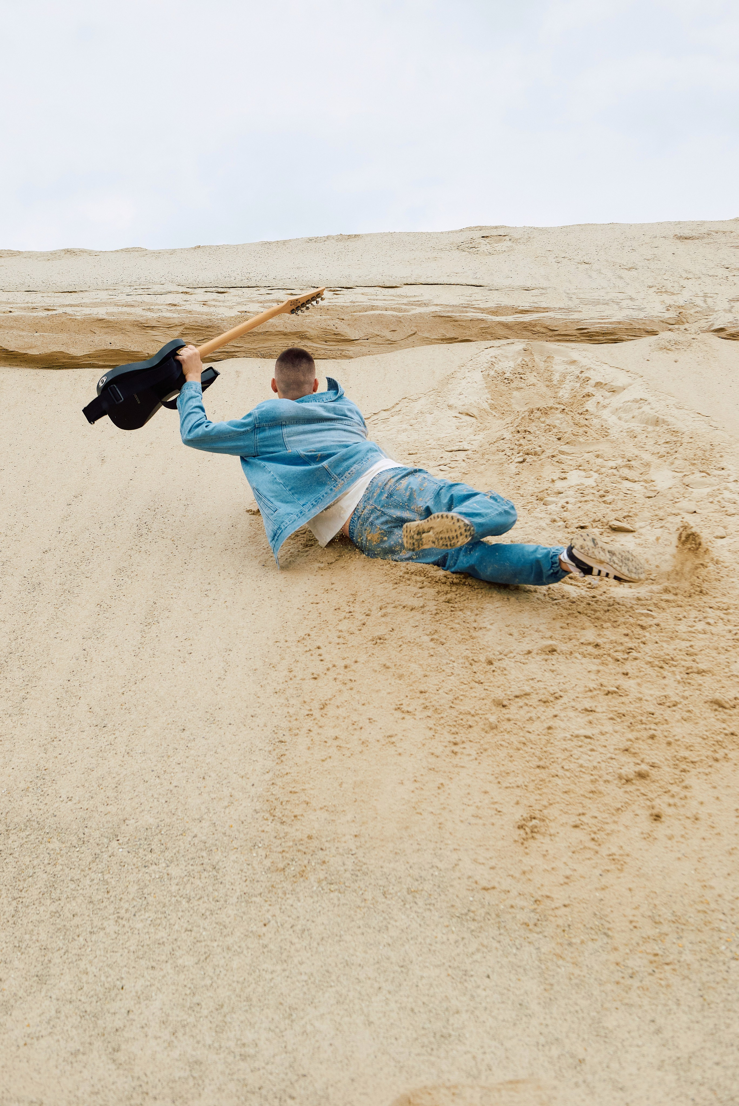 Песок гитара парень в джинсах