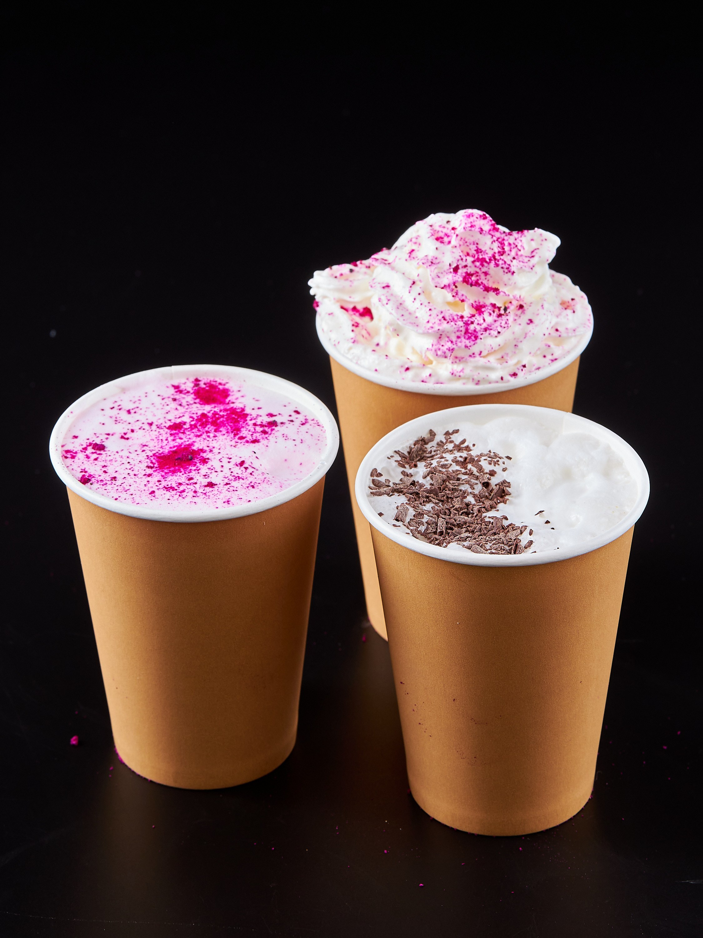 Коктейли в трех бумажных стаканах на черном фоне