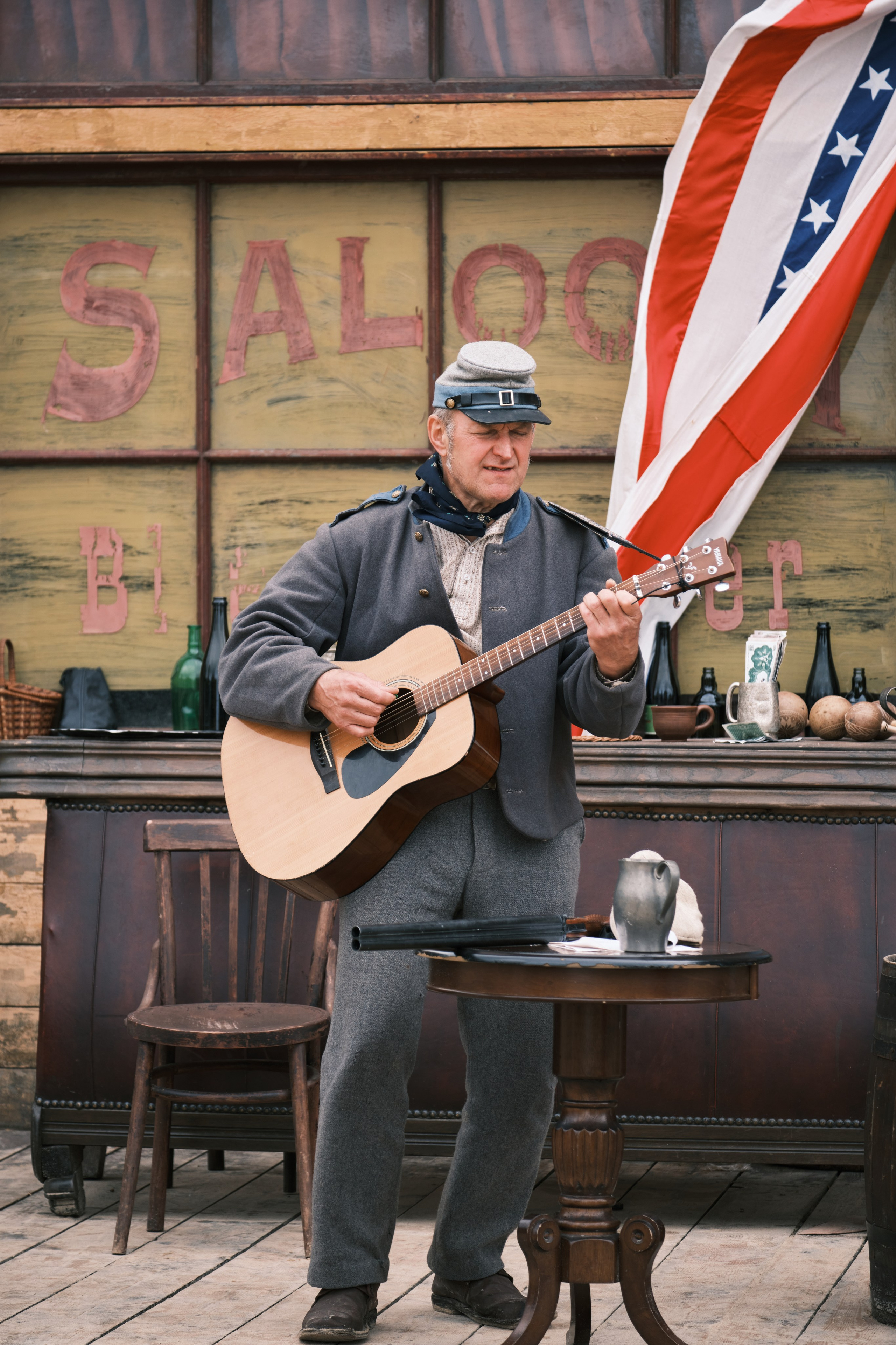 Мужчина играет на гитаре возле салона в ковбойском городке
