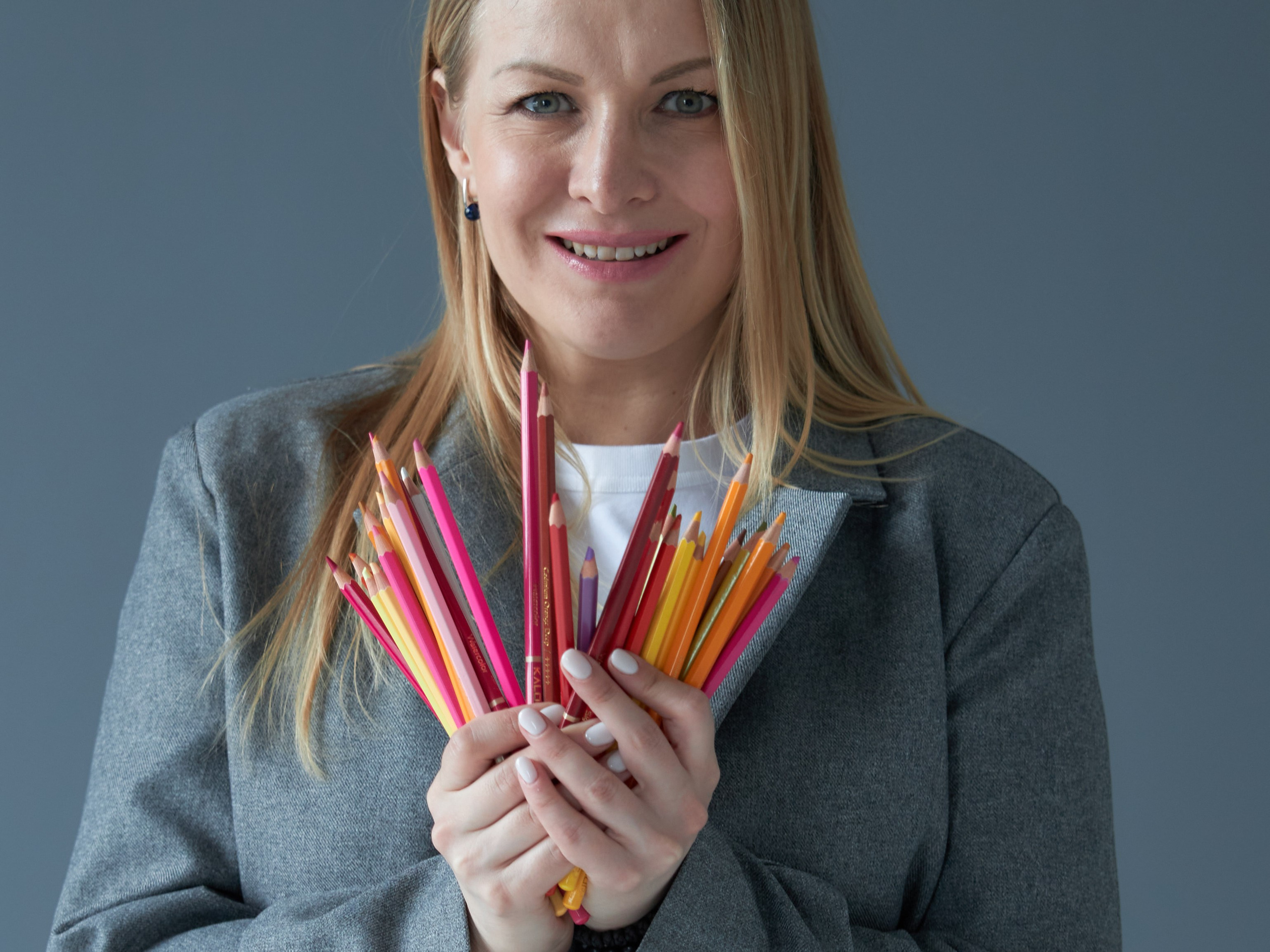 Крупный портрет женщины с длинными волосами и цветными карандашами в руках